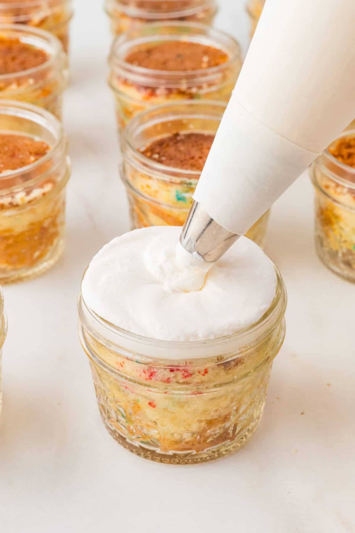 piping frosting onto a jar of cake