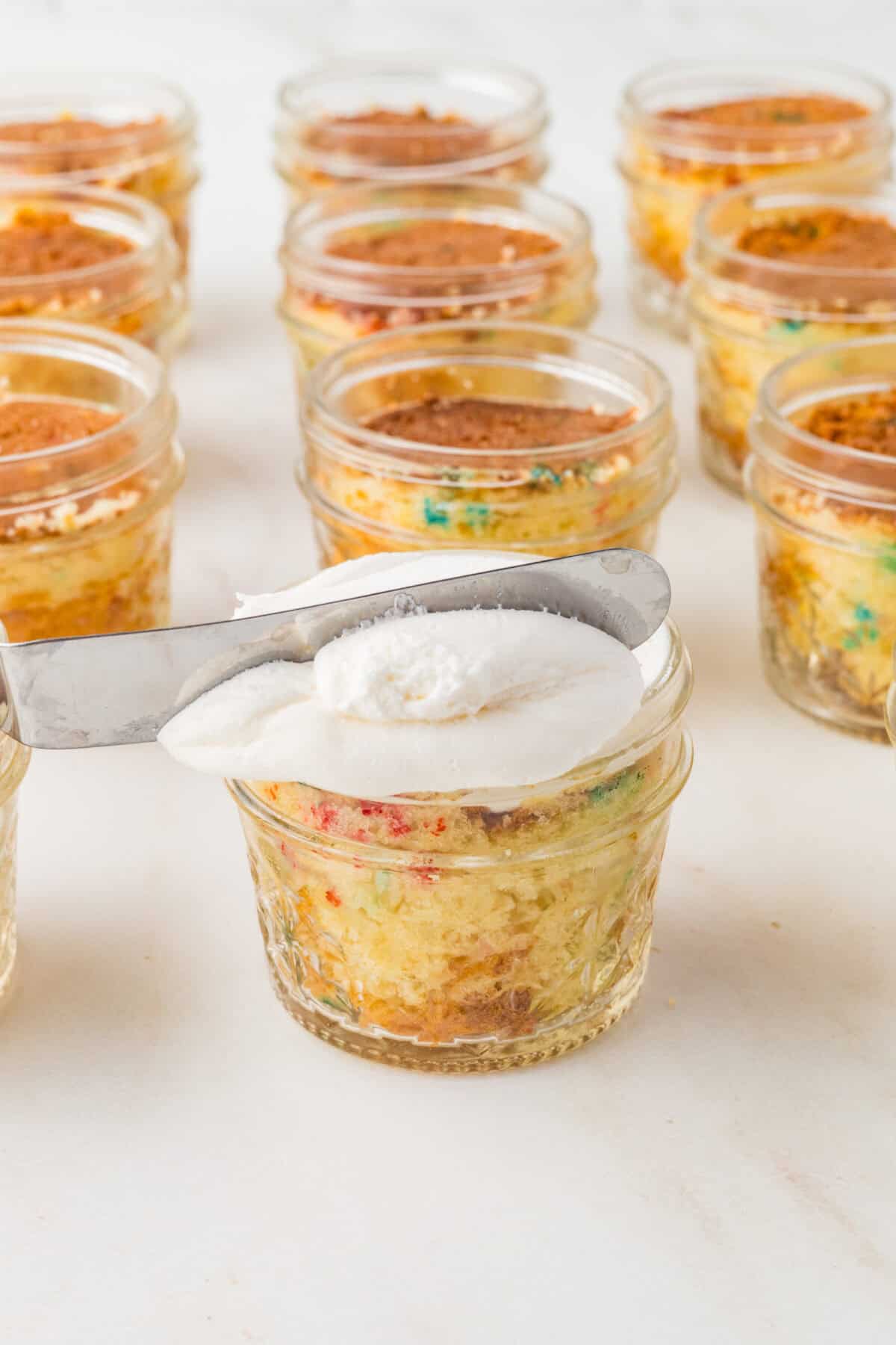using a small spatula to level frosting over a jar of cake