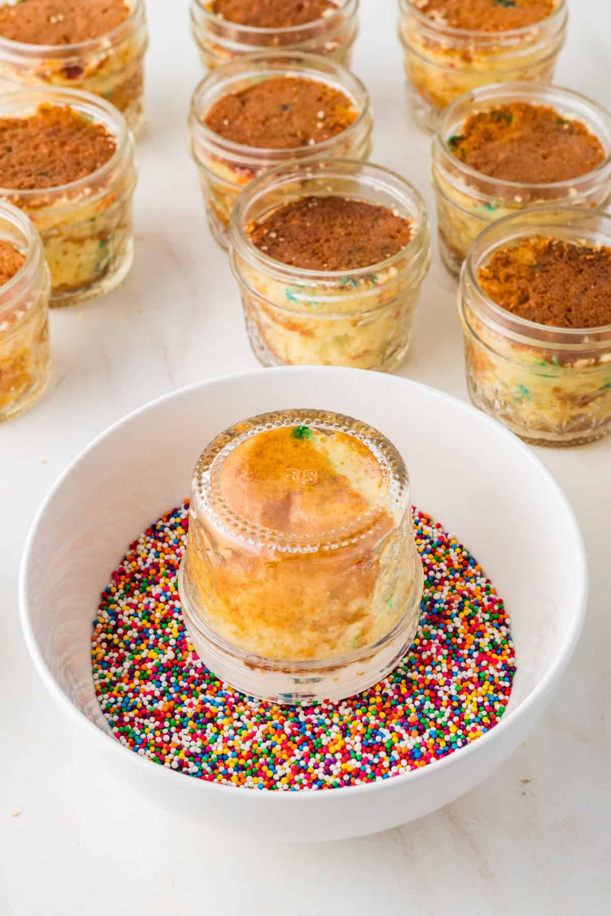 jar of cake upside down on plate of sprinkles