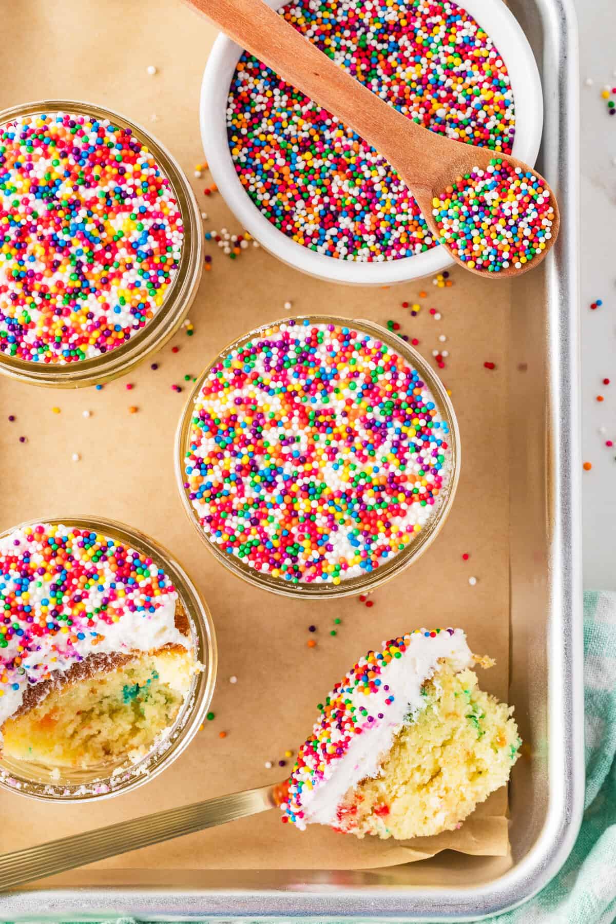 dot cakes on a cookie sheet with a bite missing from one and sprinkles in a bowl next to them