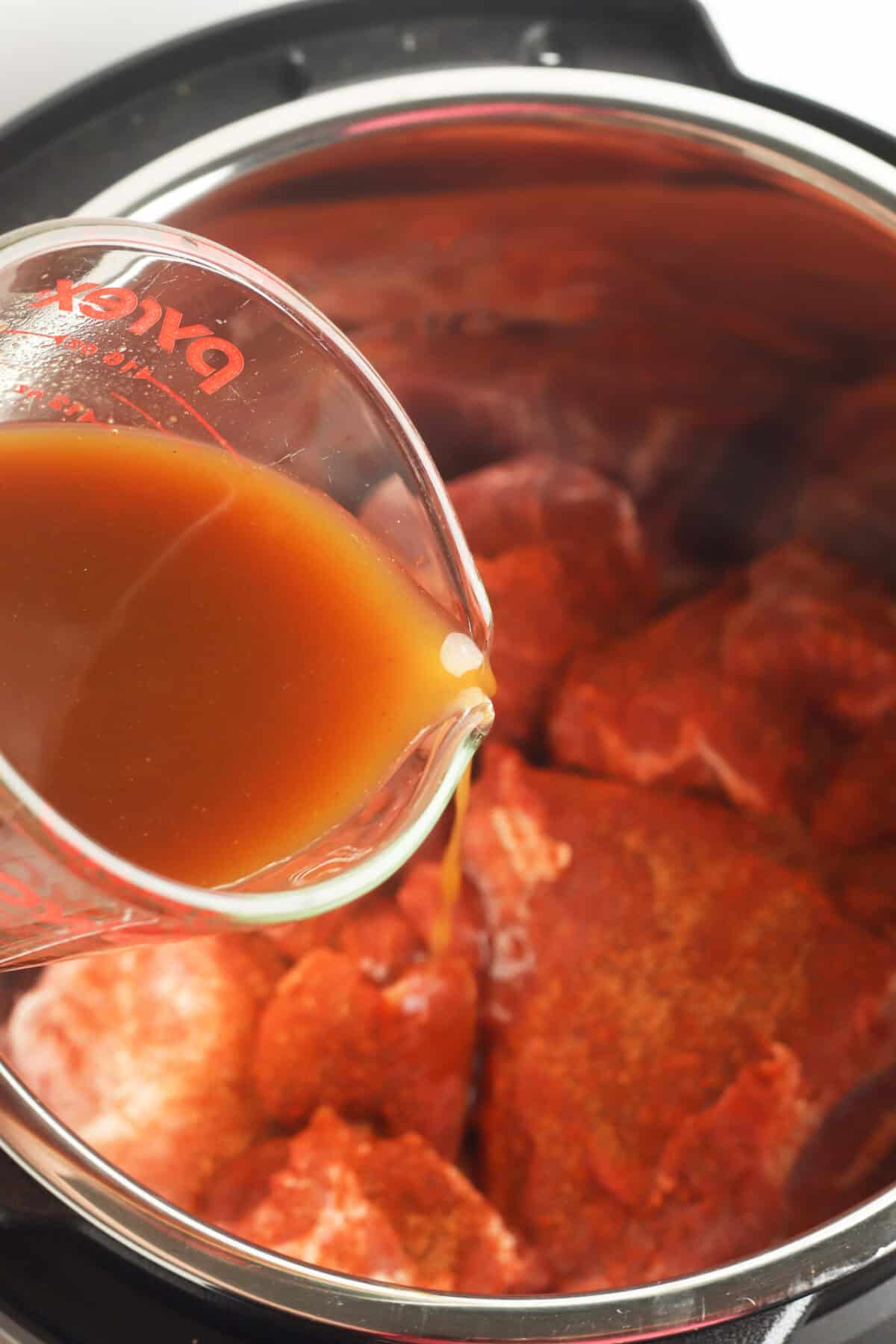 pouring bbq sauce mixture over pork in instant pot