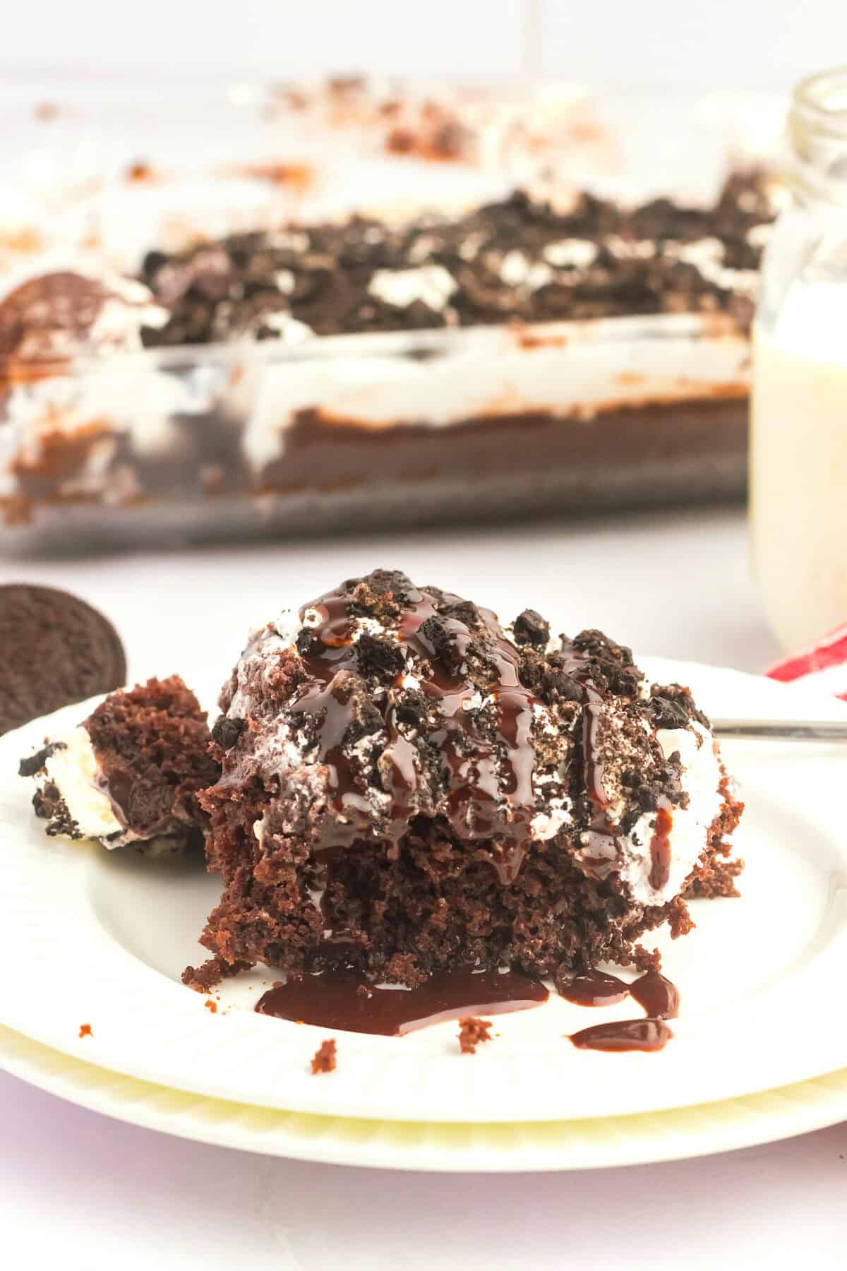 slice of cake next to pan of oreo poke cake