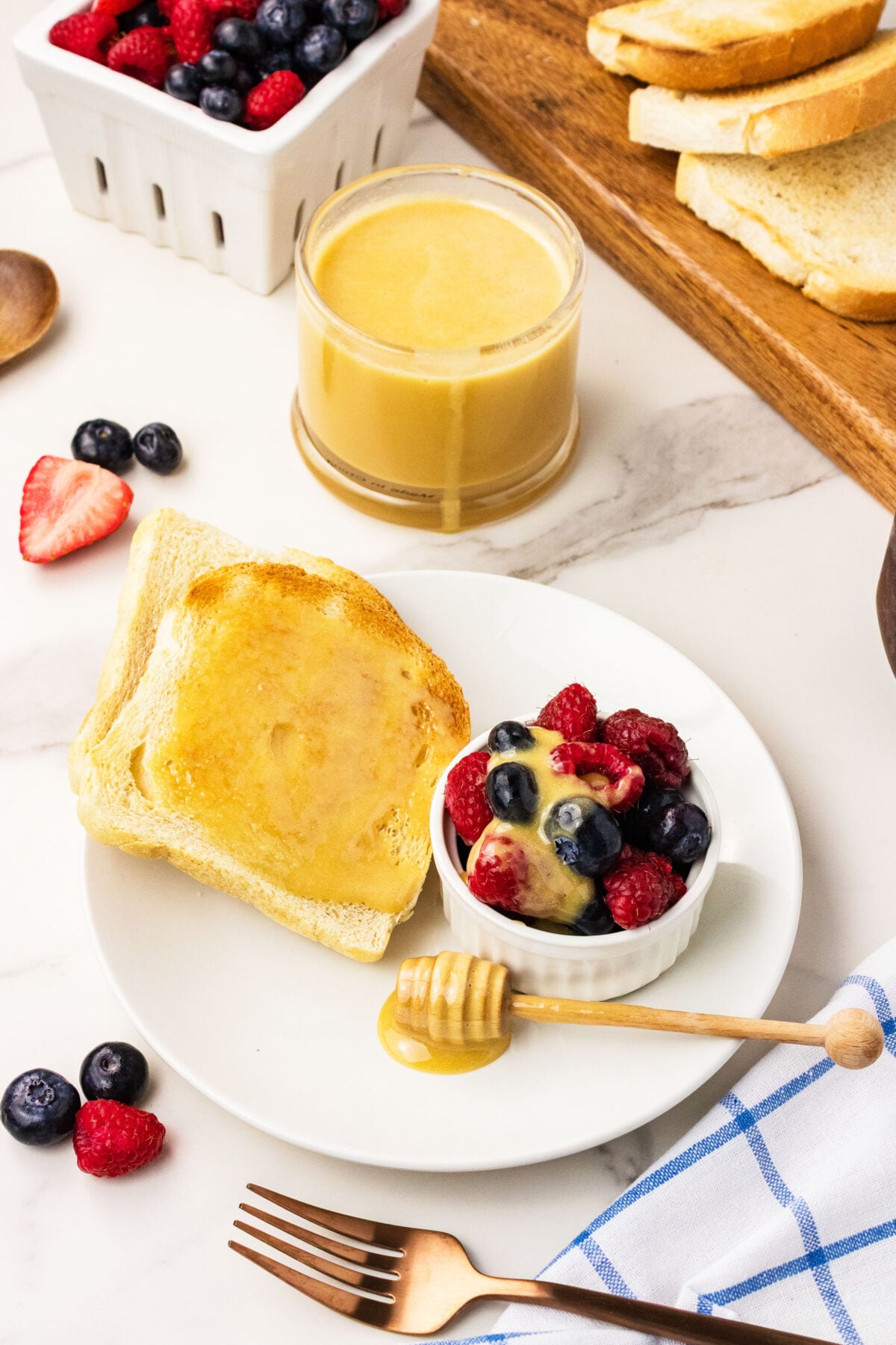a bowl of fruit with honey being drizzled over it next to honey toast