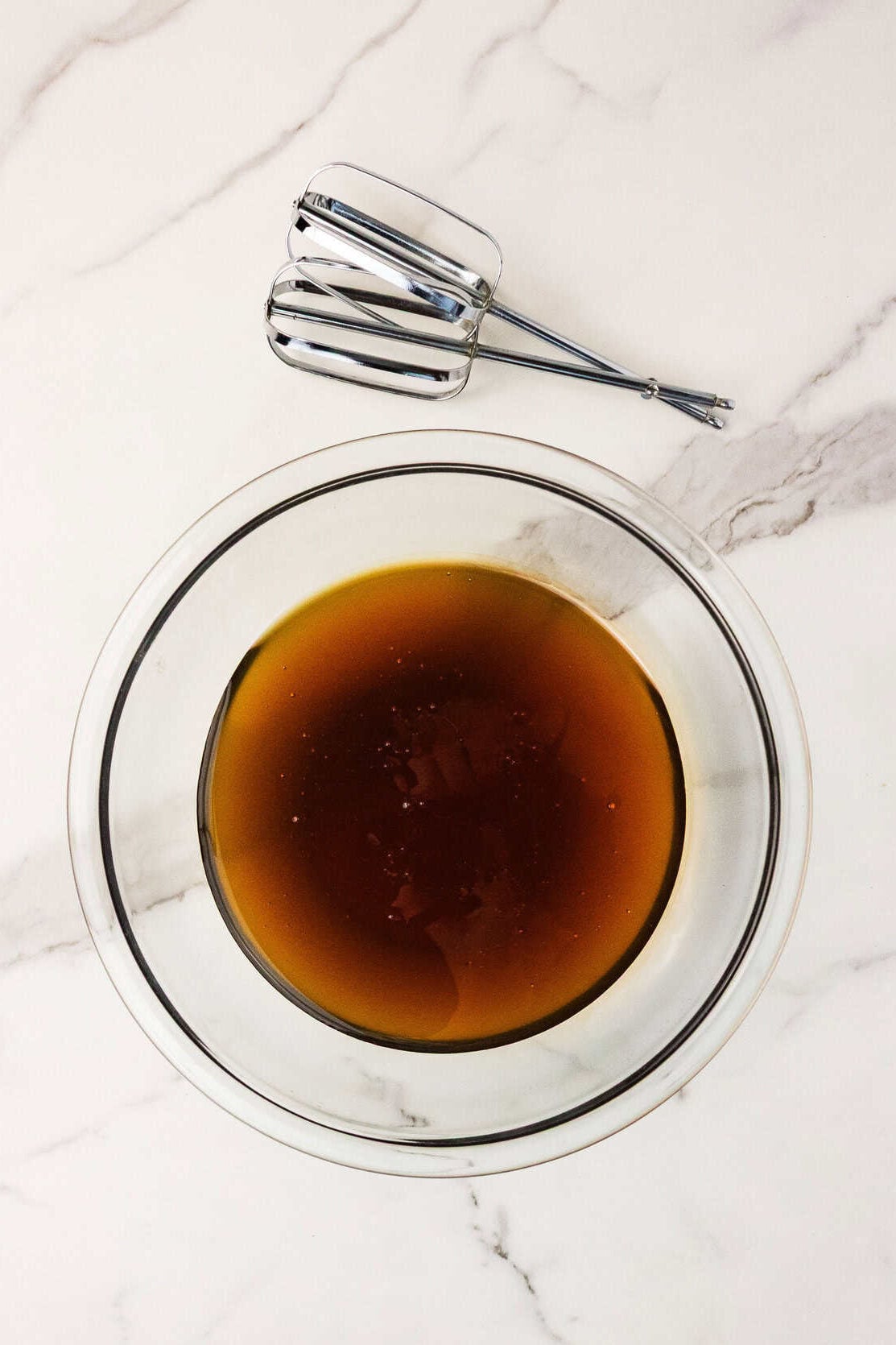 raw honey in a mixing bowl with beater blades next to it on the counter