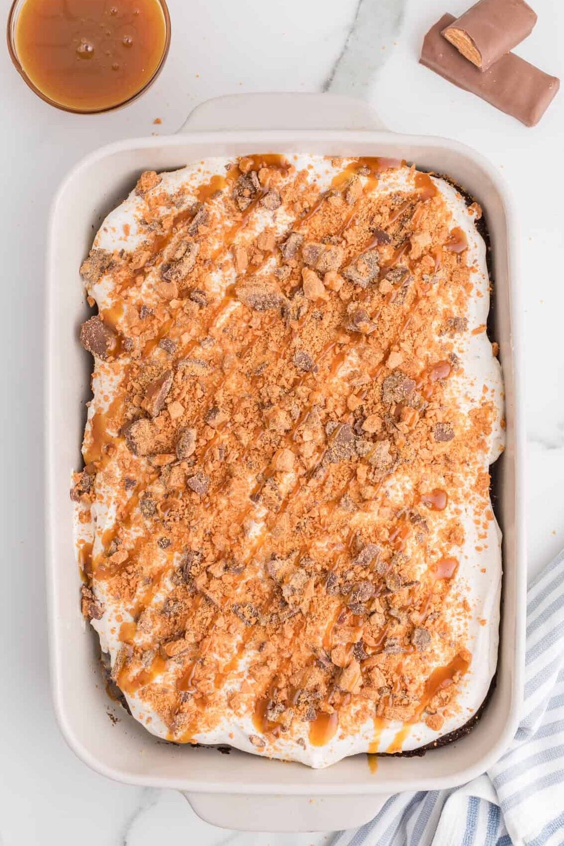 butterscotch drizzled over chopped butterfingers on a poke cake