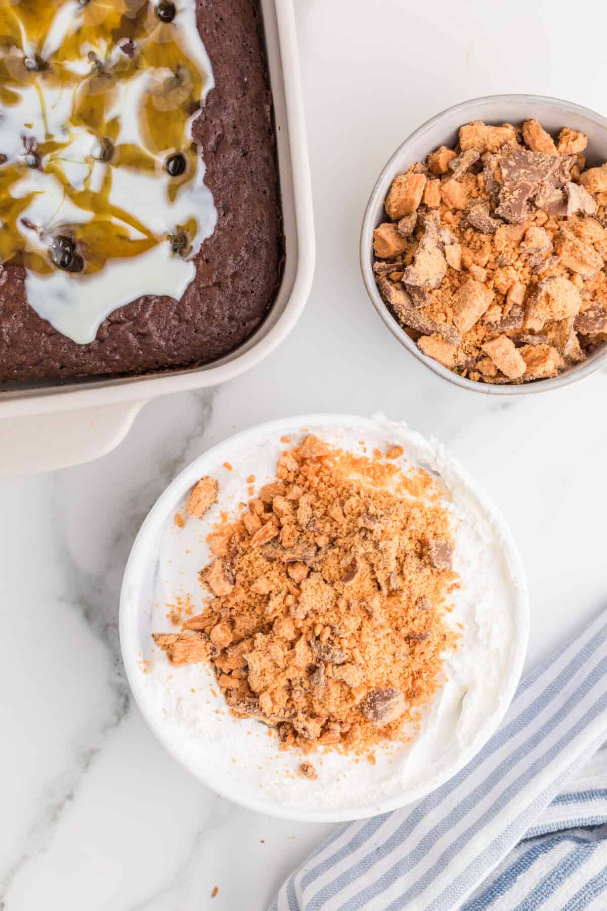 chopped butterfinger on top of whipped cream in a bowl