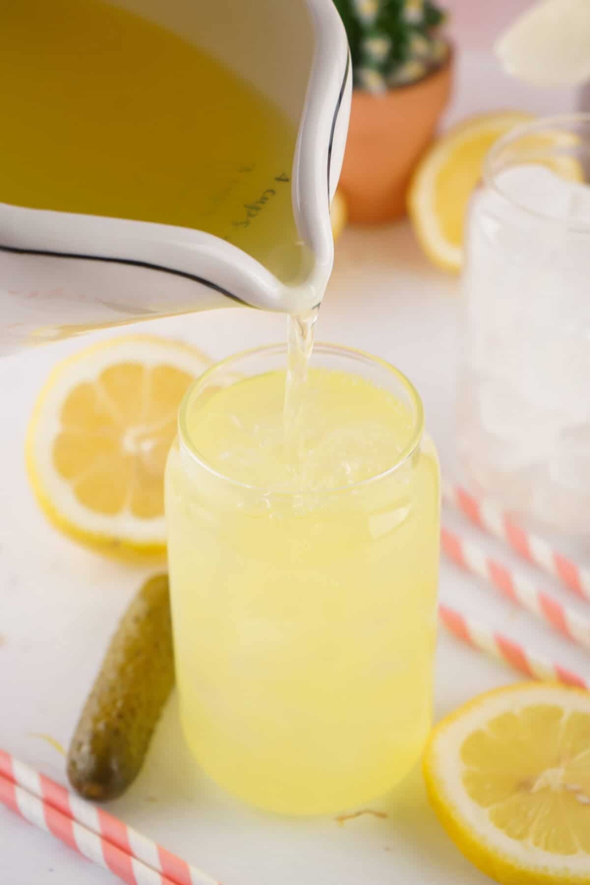 dill pickle lemonade being poured from a pitcher into a glass