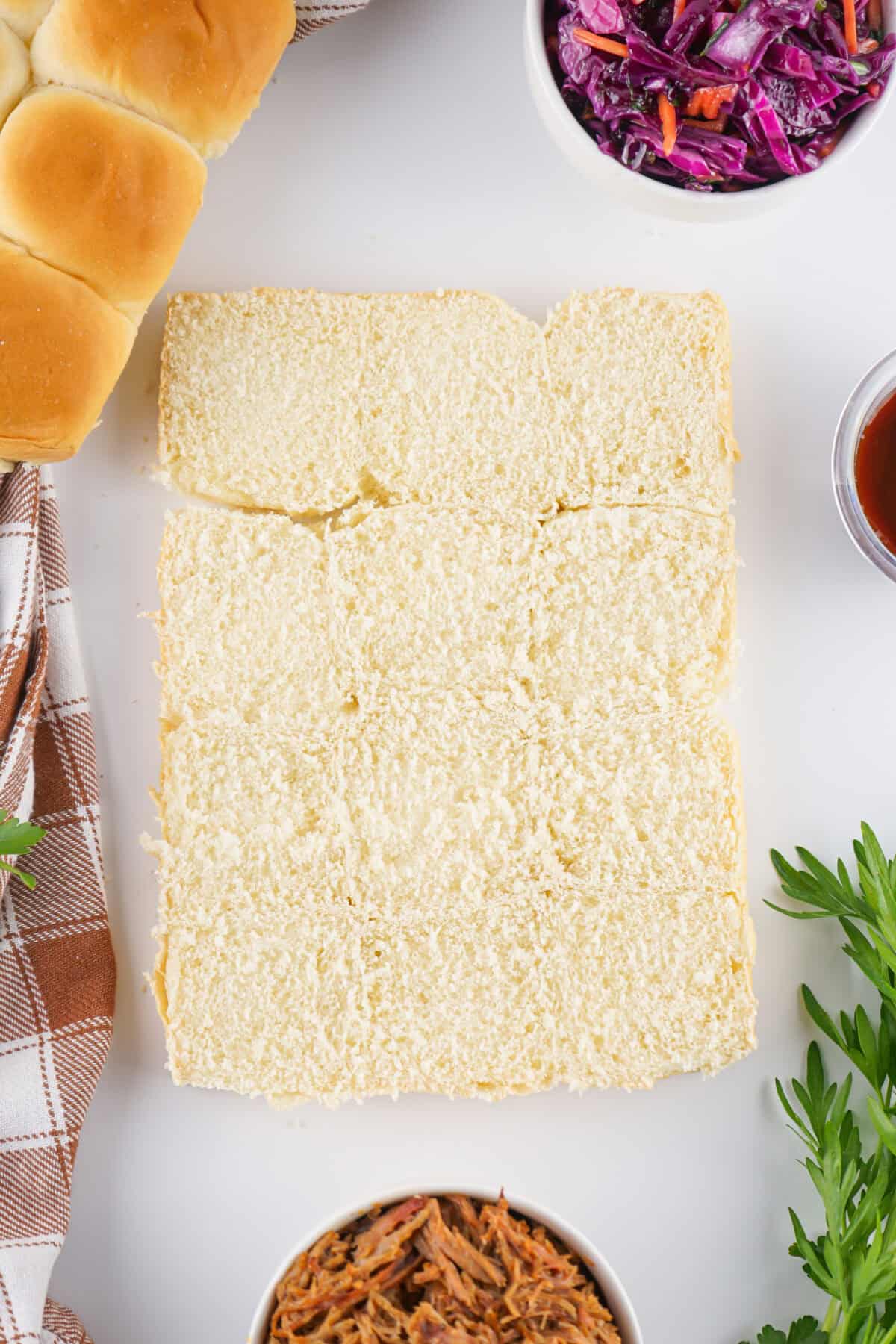 bottom half of hawaiian rolls with ingredients around the bread