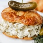 dill pickle chicken salad on a croissant with a dill pickle on top