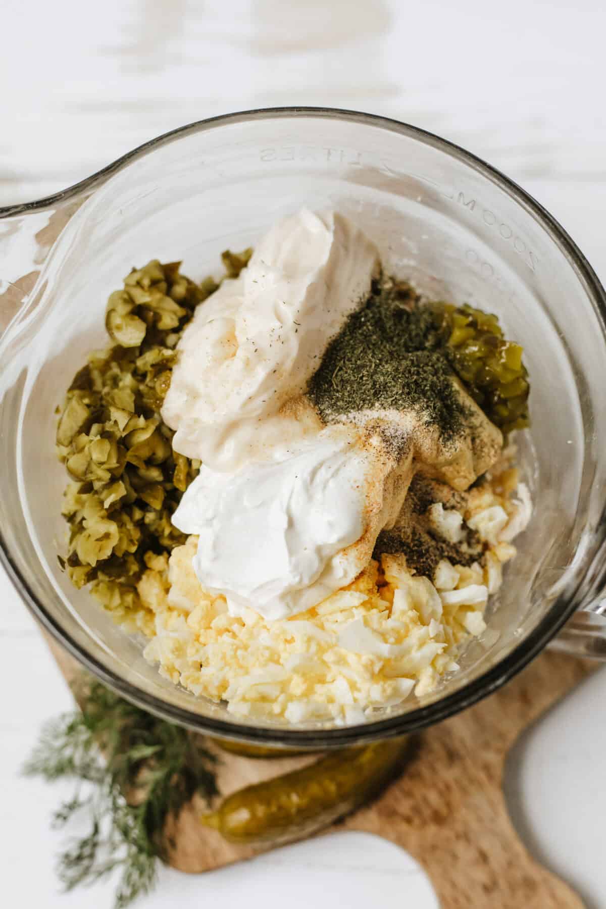 creamy dressing ingredients added to bowl with chicken salad ingredients