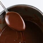hot fudge sauce dripping off a spoon over a saucepan