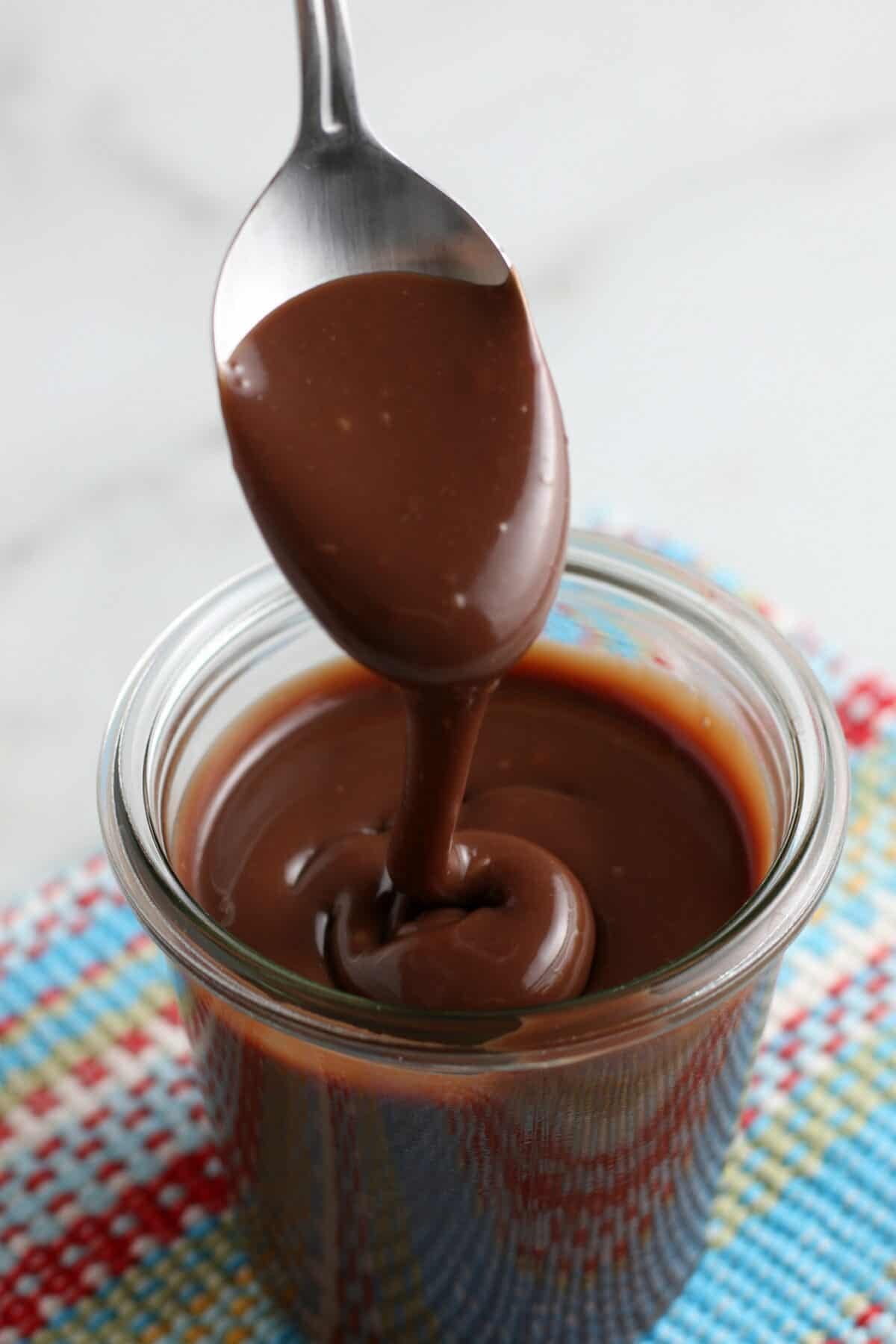 hot fudge sauce in a cup with a spoon dripping