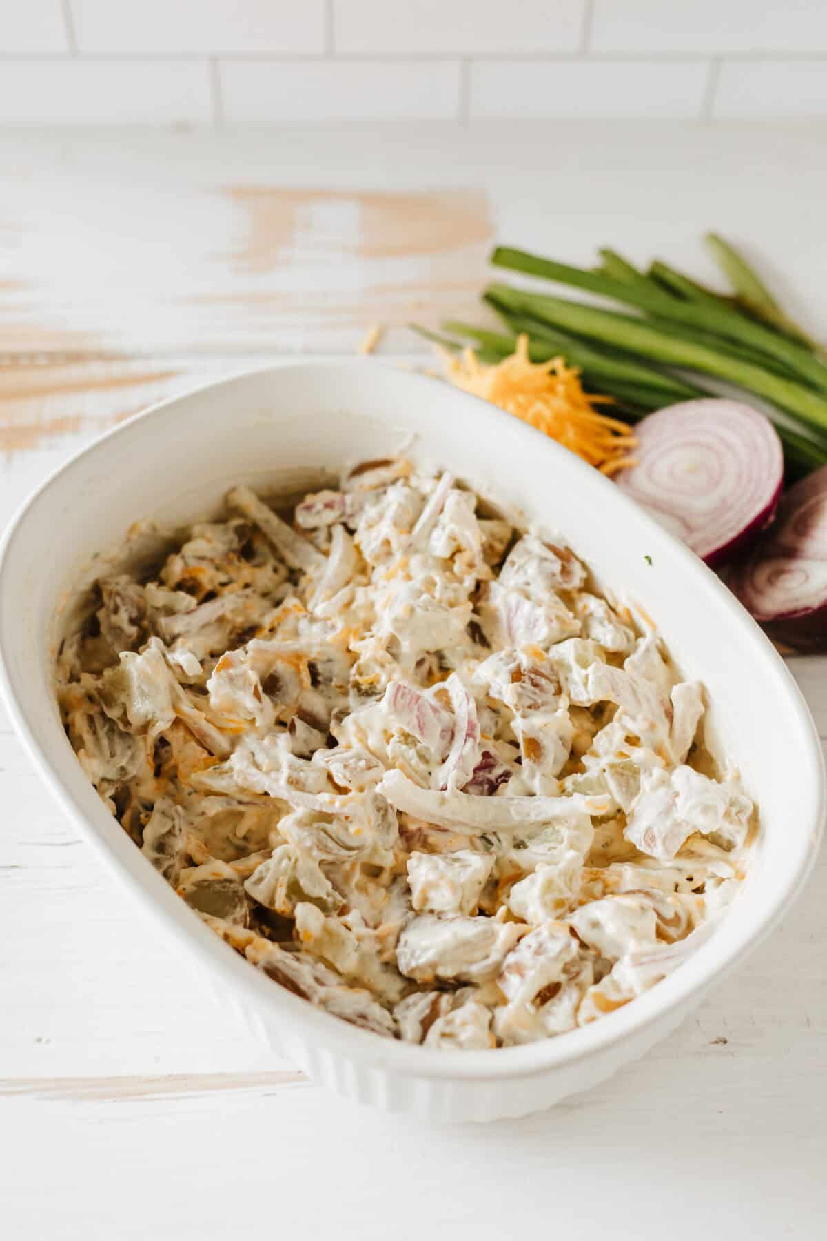 baked potato salad mixed up with dressing in serving dish