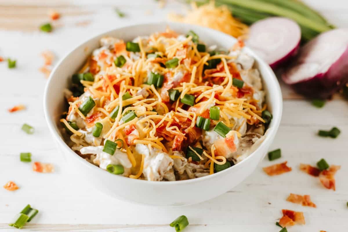 loaded baked potato salad in a white bowl