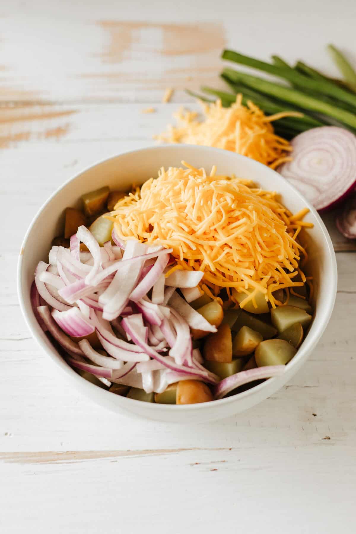 potatoes, onions, cheese and bacon in a mixing bowl
