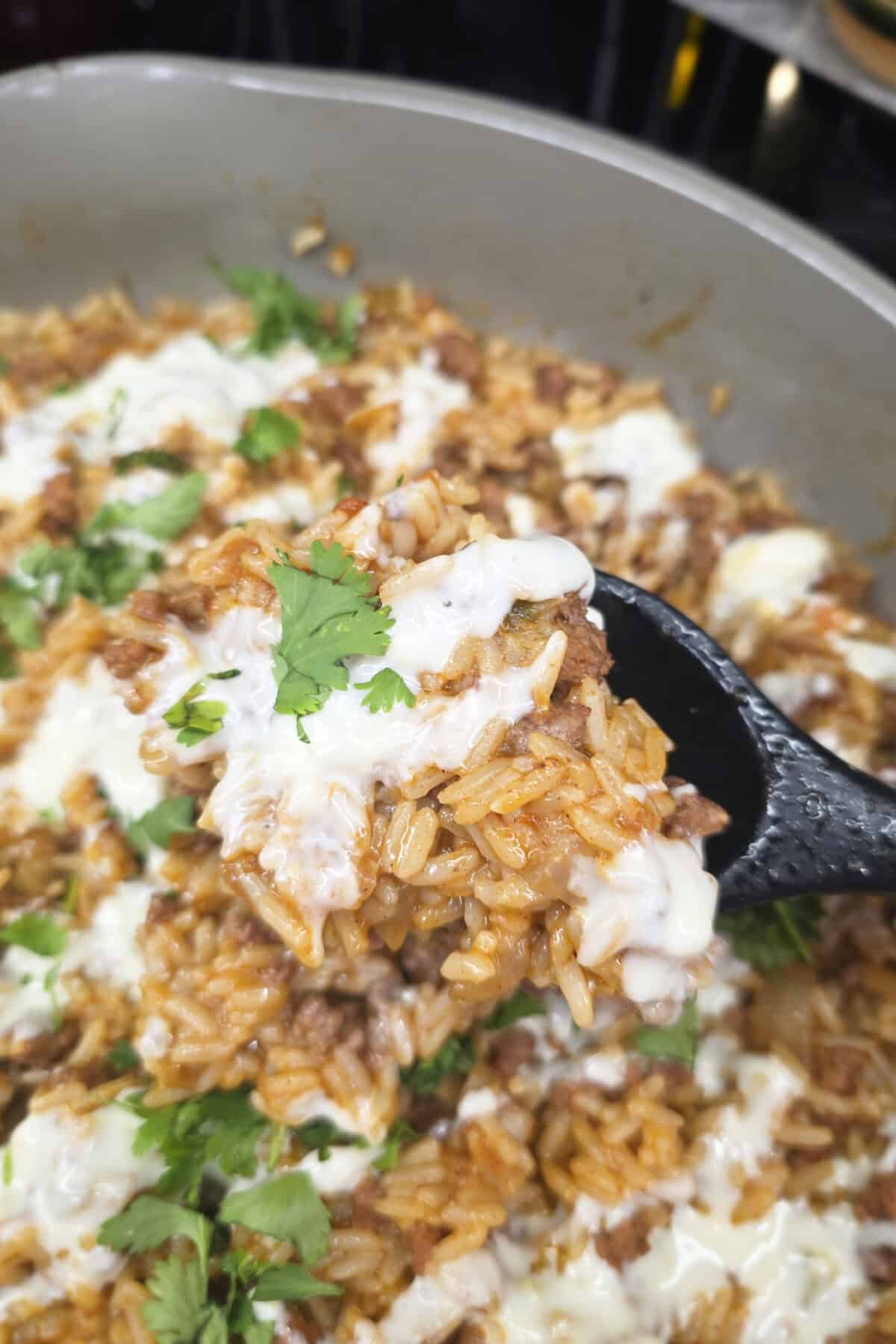 taco rice with queso and cilantro in a skillet with a spoon