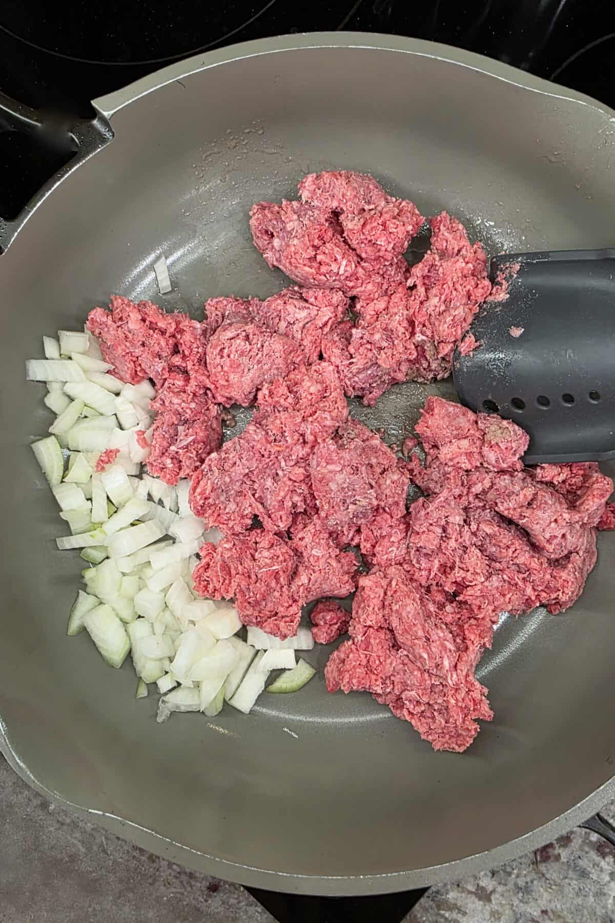 raw ground beef and diced onion in a large skillet