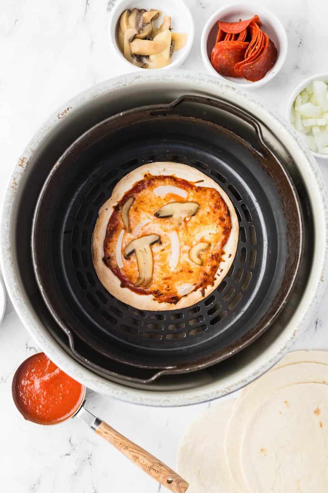air fryer pizza with mushrooms and onions in air fryer basket