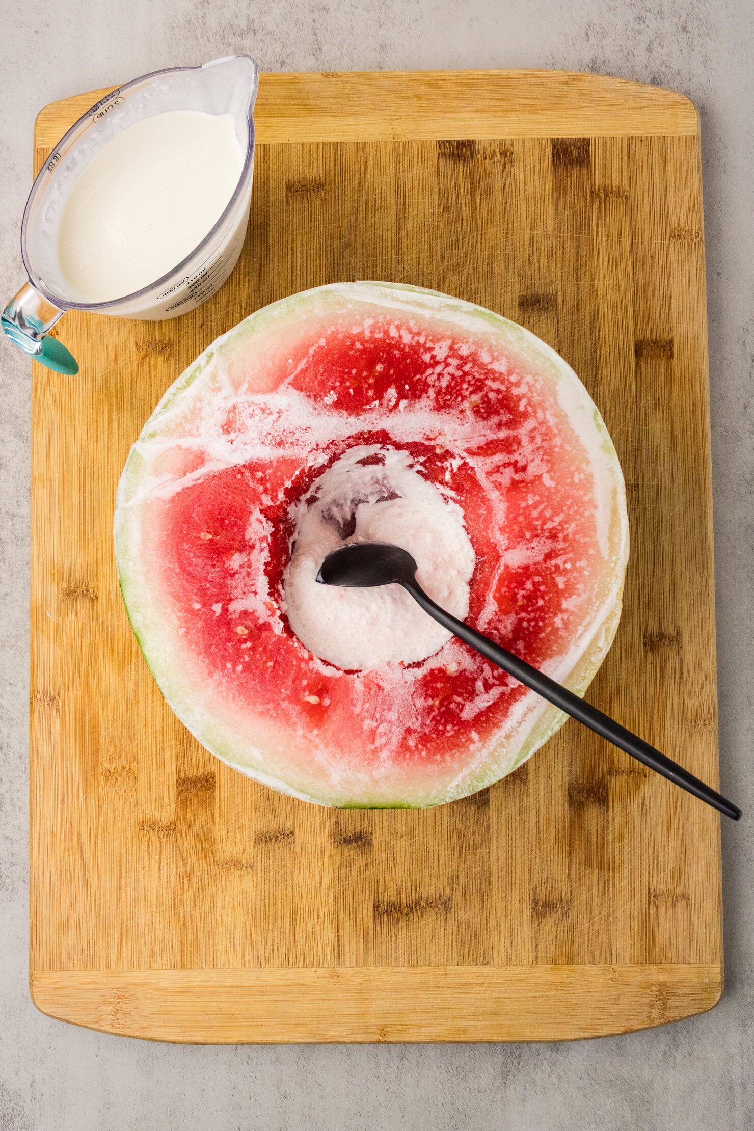spoon scraping frozen heavy cream in hollowed out watermelon
