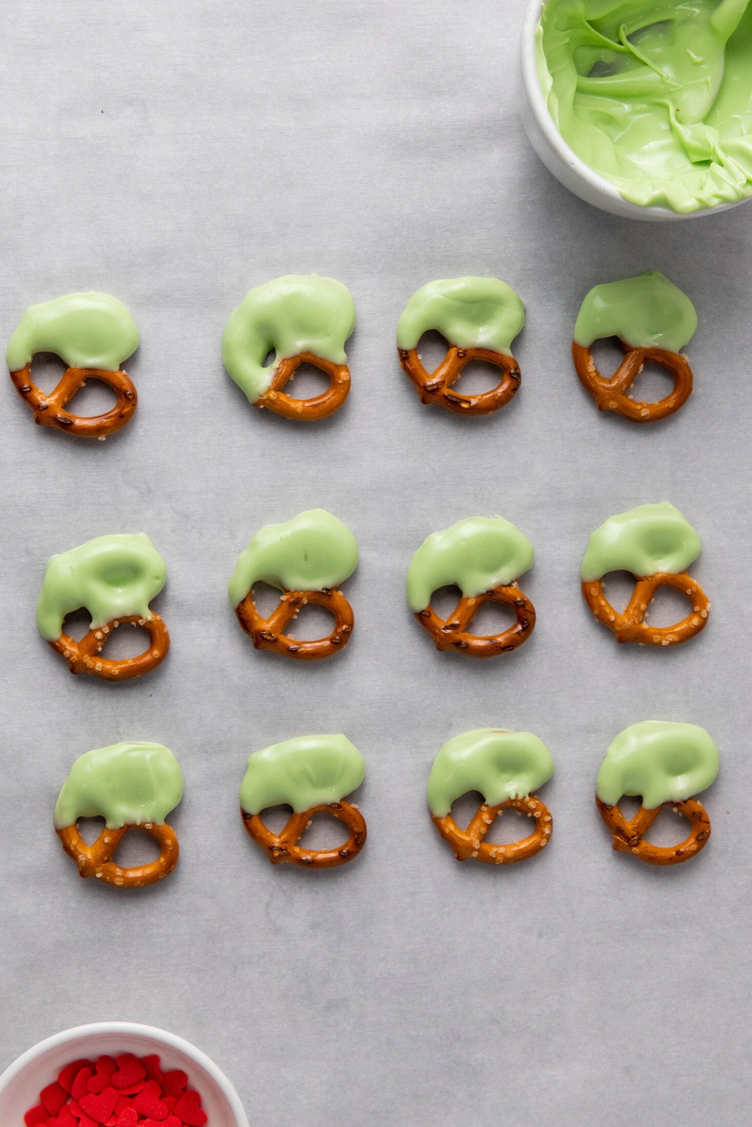 pretzels dipped in green candy melts on parchment paper