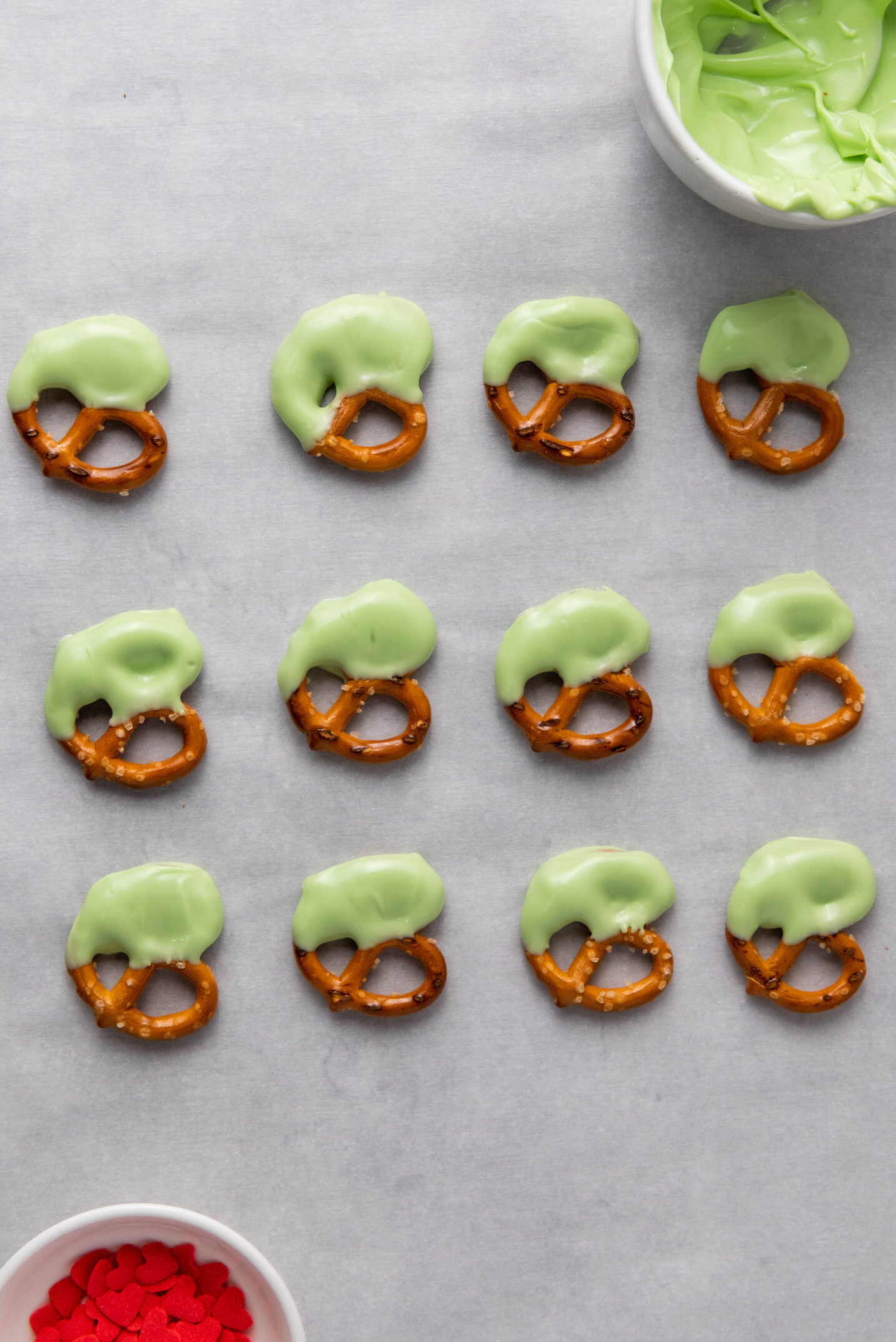 pretzels dipped in green candy melts on parchment paper