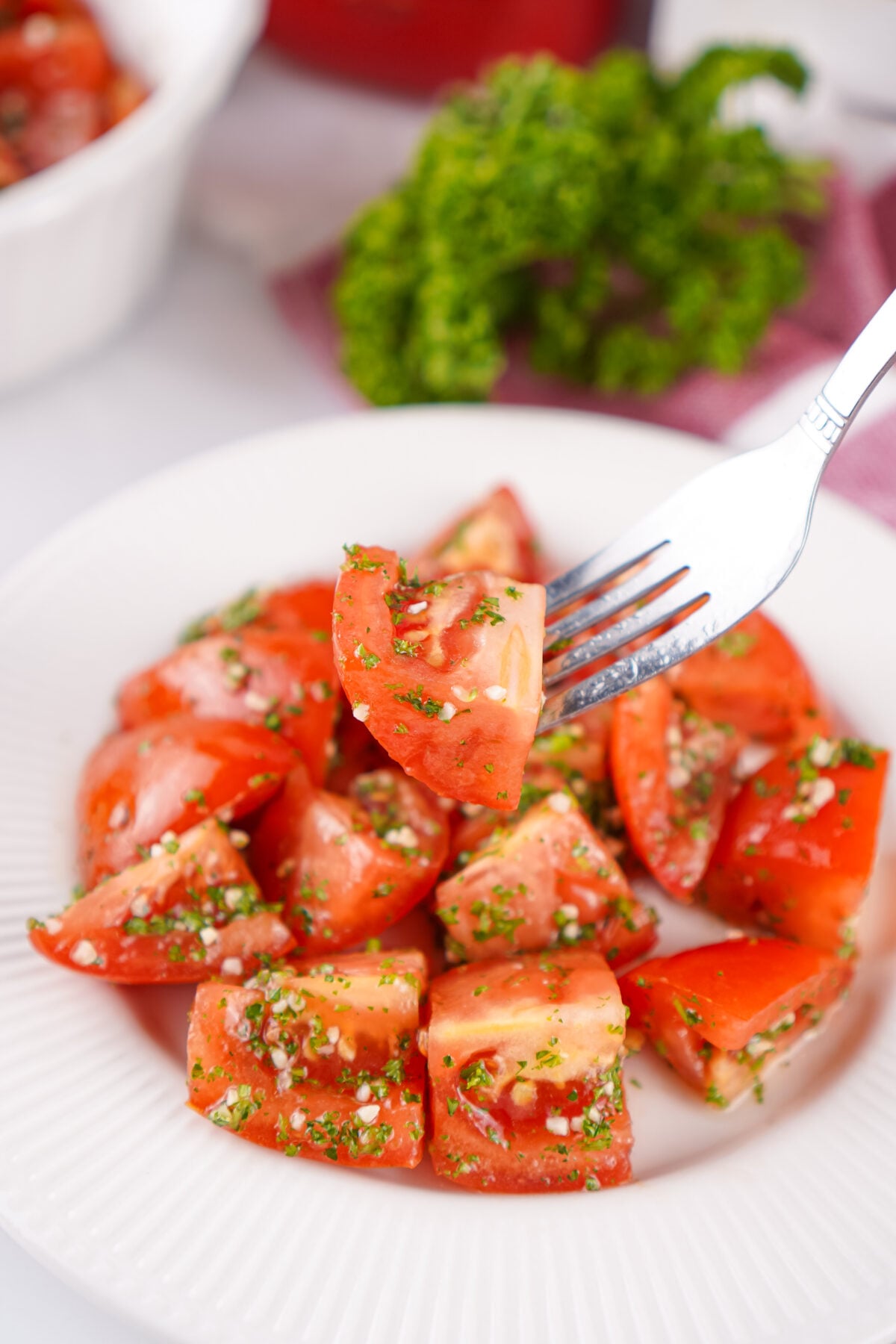 bowl of marinated tomatoes with a bite on a fork