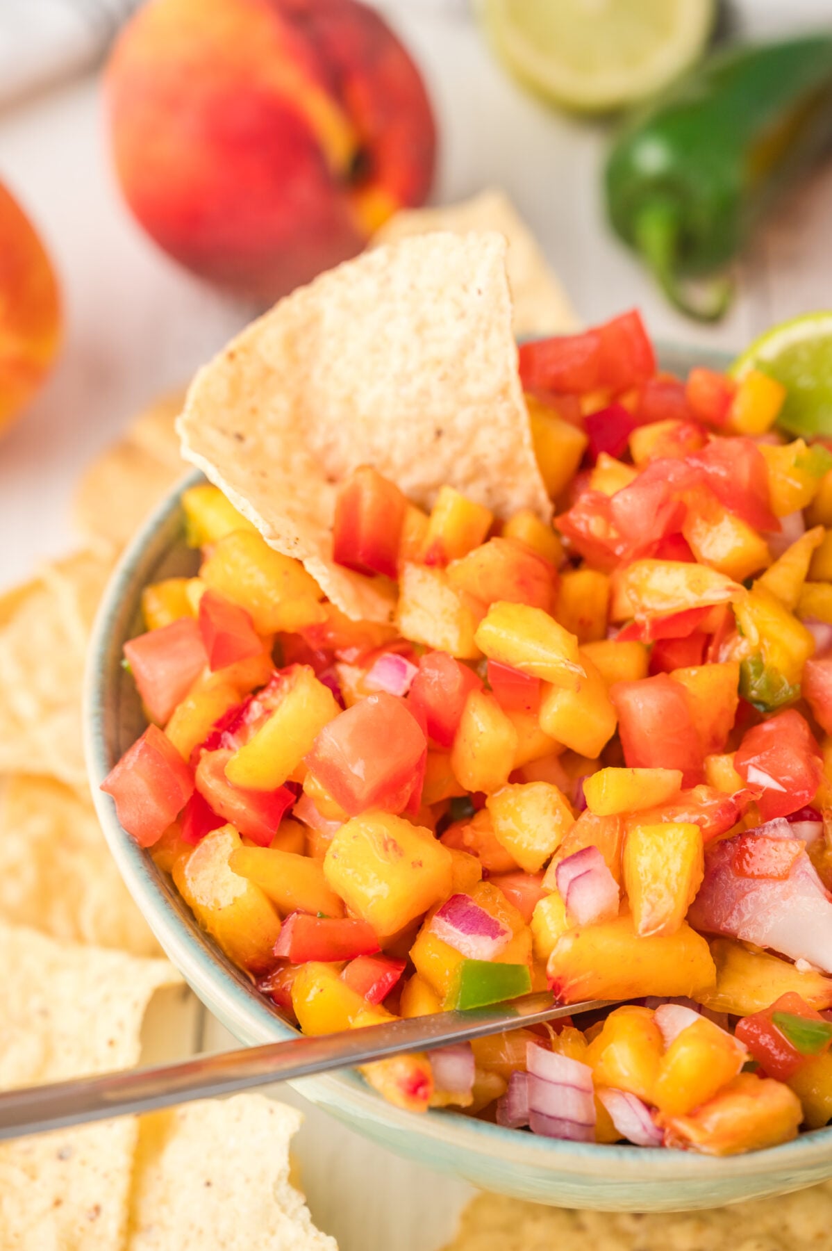 peach salsa in a bowl with tortilla chip and spoon