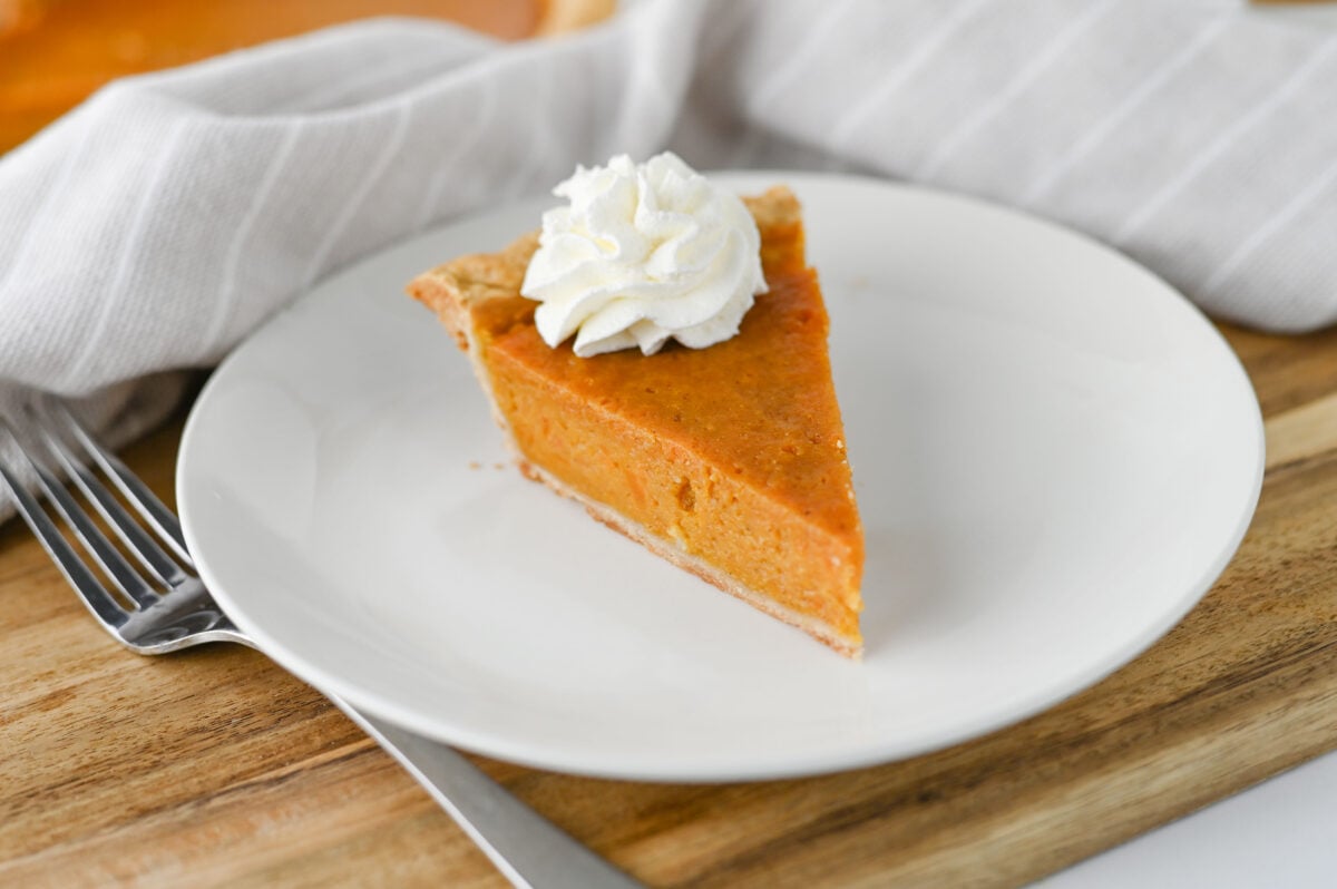 a slice of sweet potato pie with whipped cream on a white plate