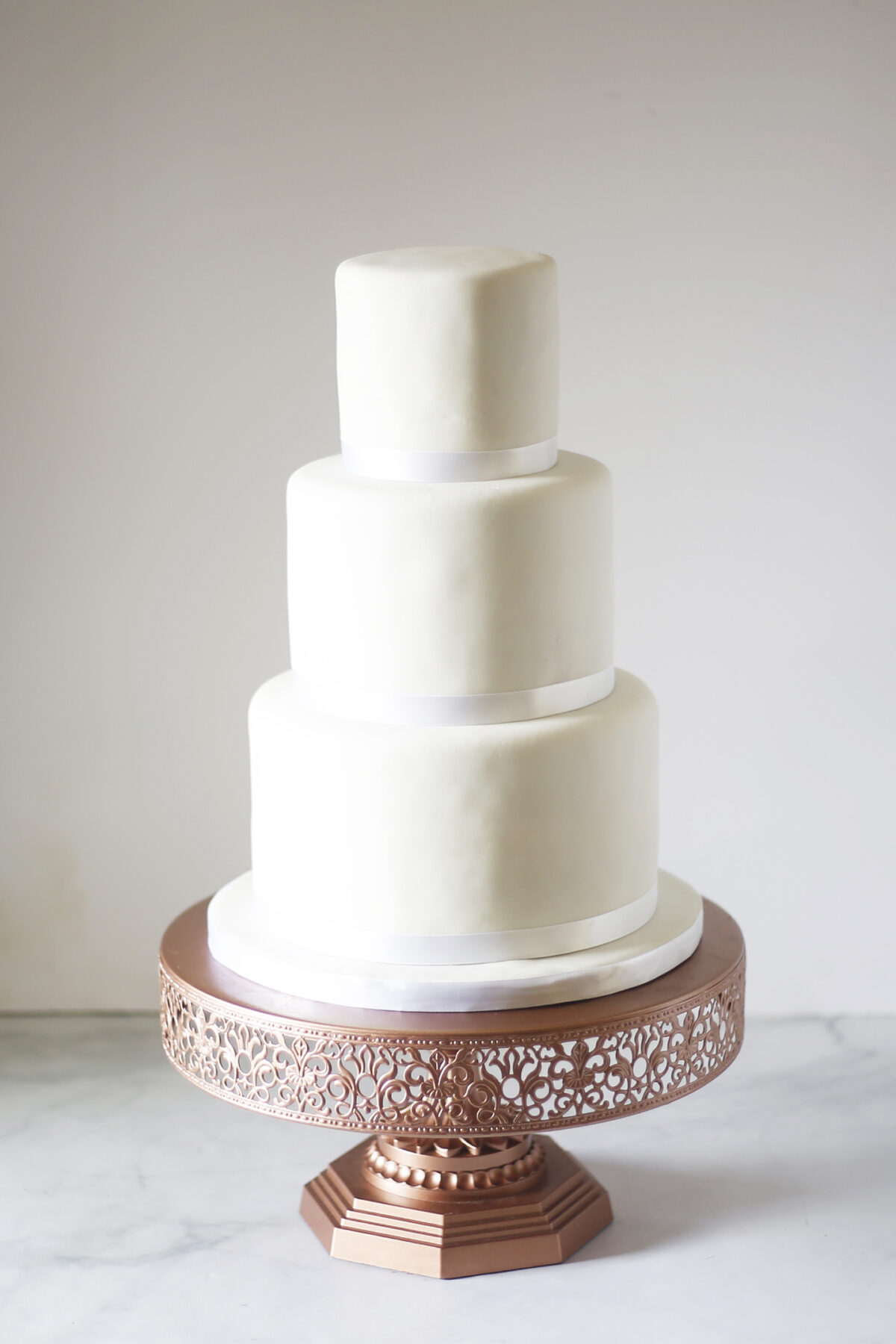 white homemade marshmallow fondant wedding cake on rose gold stand