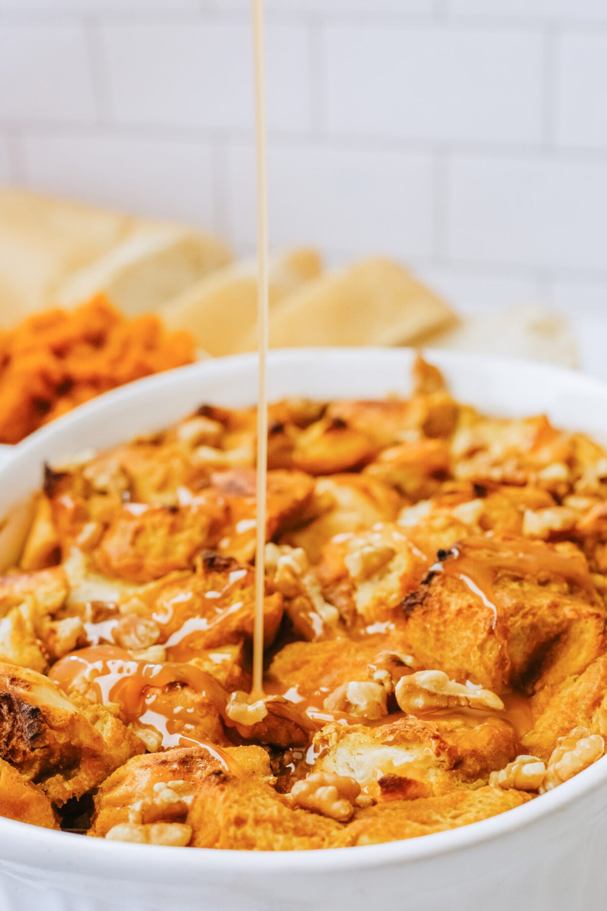 pumpkin bread pudding with caramel sauce being drizzled on the top