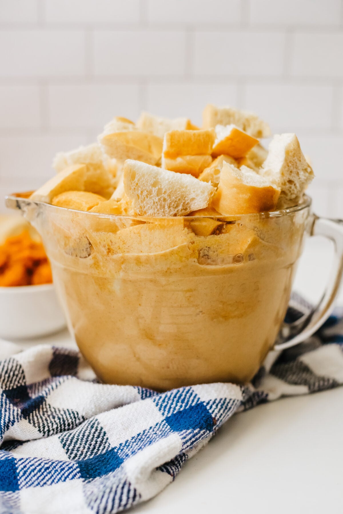 mixing bowl full of cubed bread with pumpkin mixture