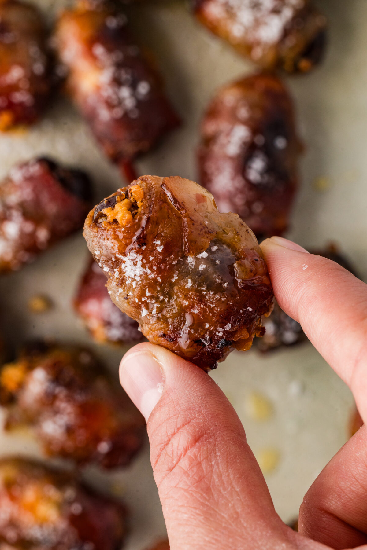 a hand holding a bacon wrapped date