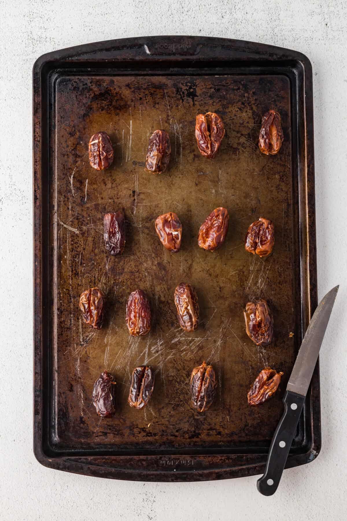 pitted dates with a slit down the middle of each - all on a baking sheet