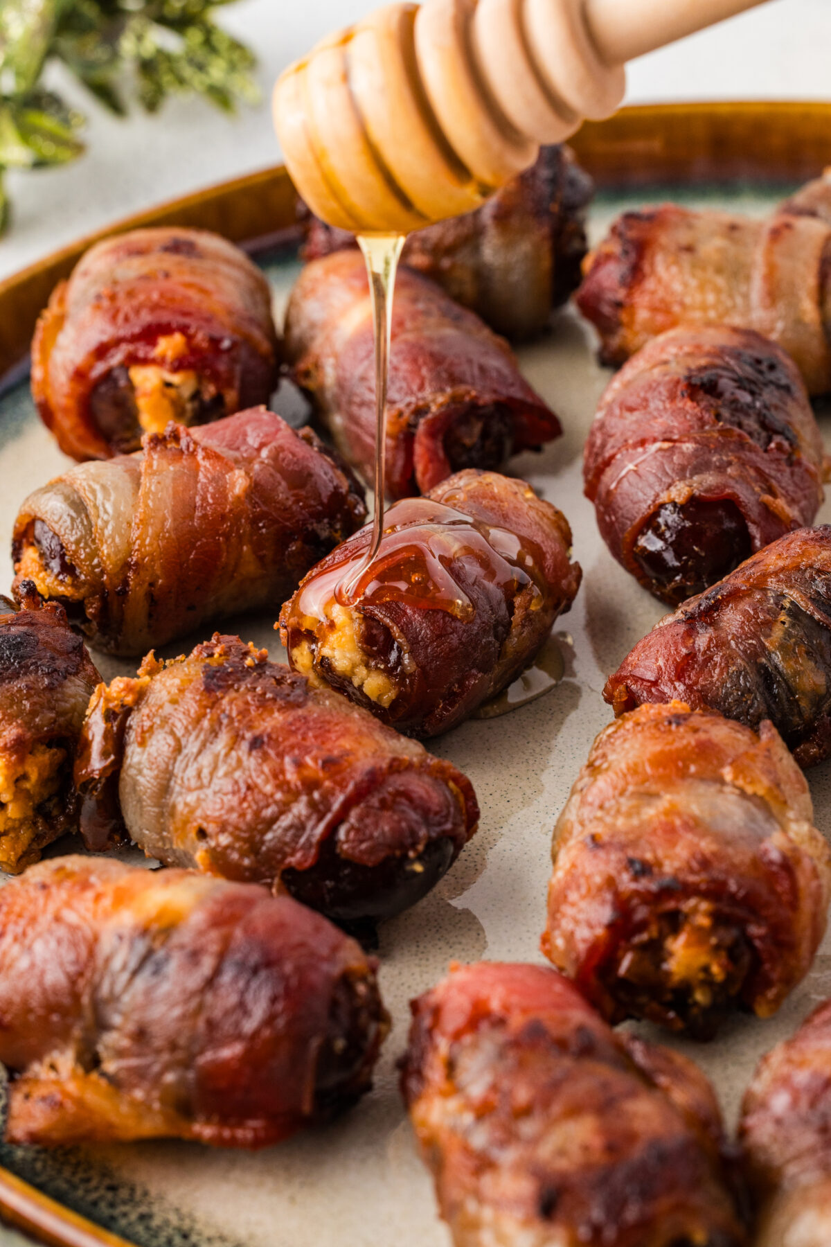 honey being drizzled over bacon wrapped dates