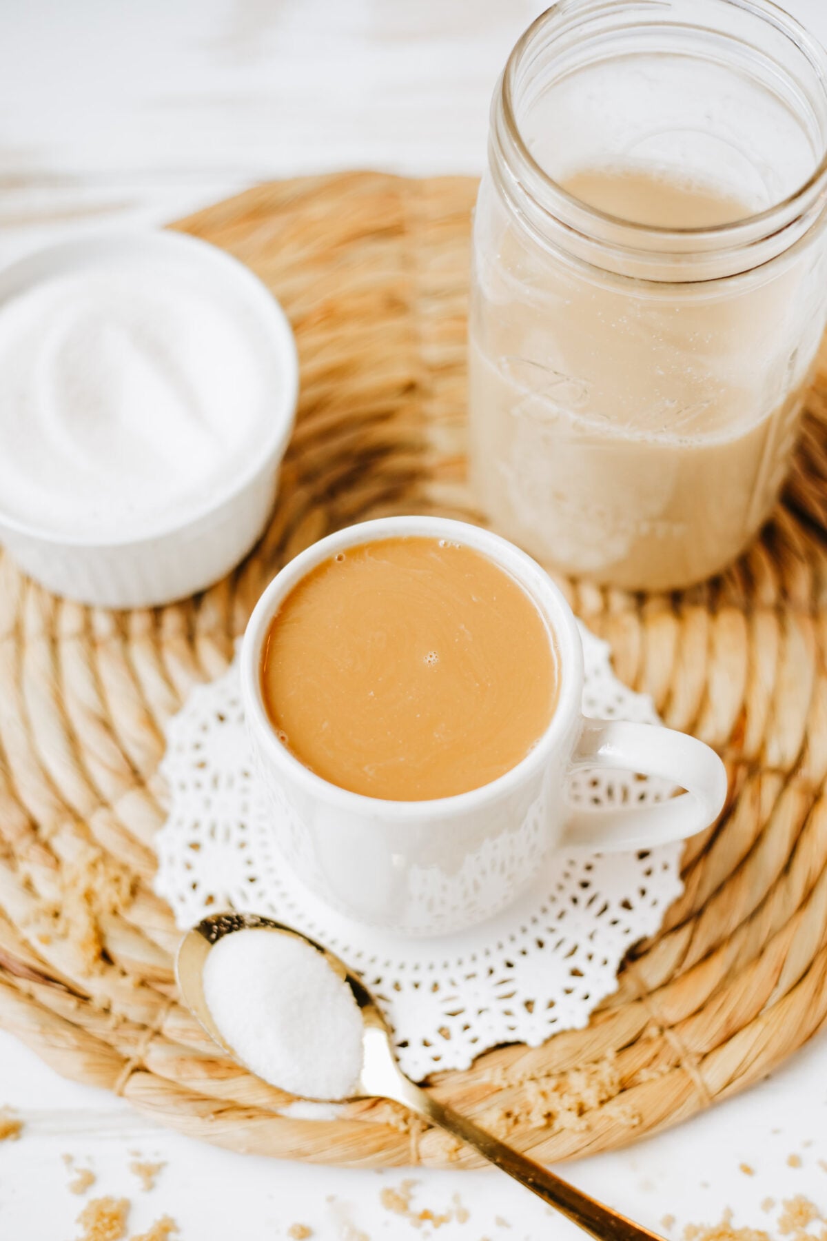cup of coffee with brown sugar coffee creamer and a spoon of sugar