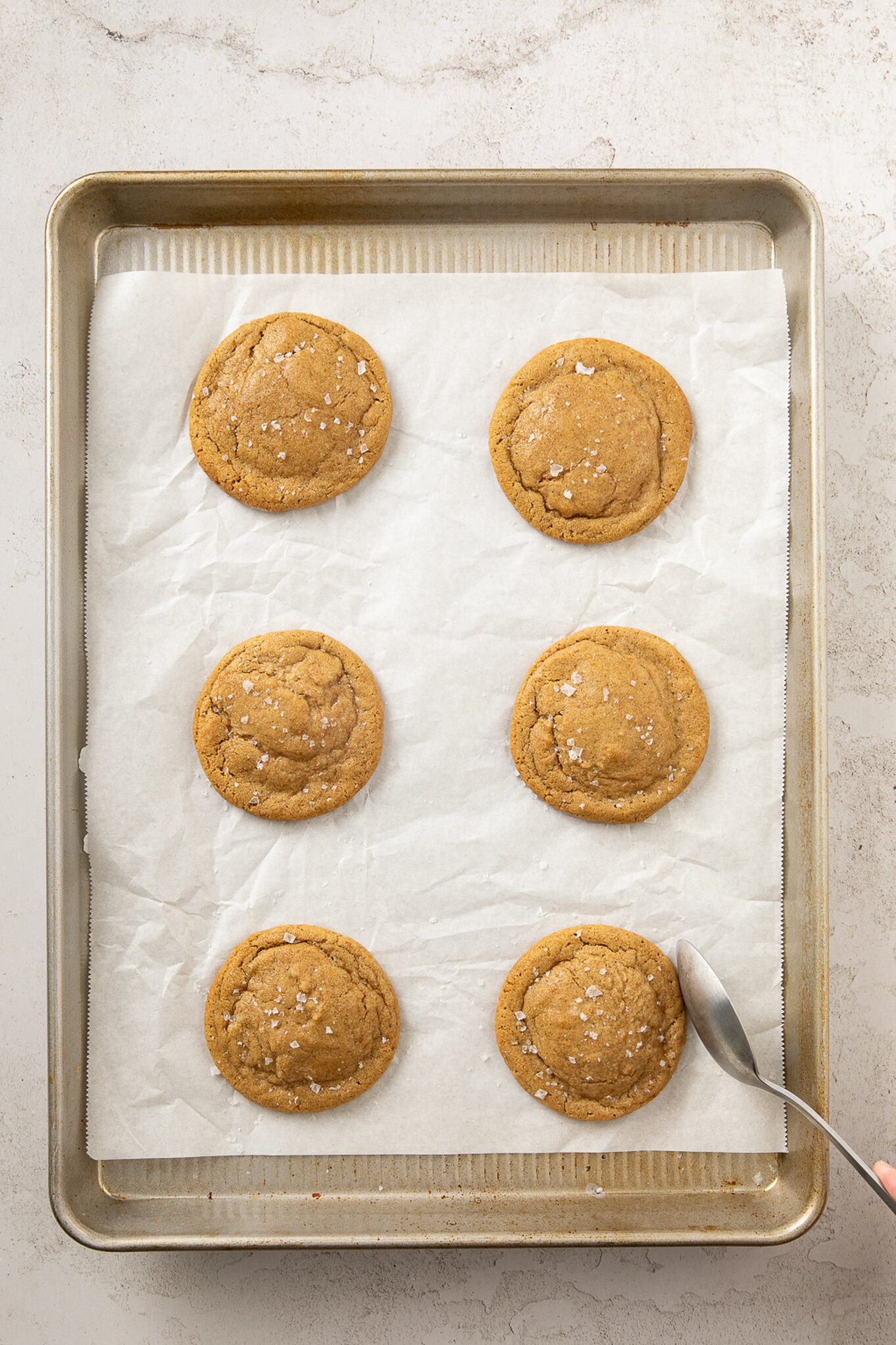 using a spoon to shape the warm cookies into perfect circles