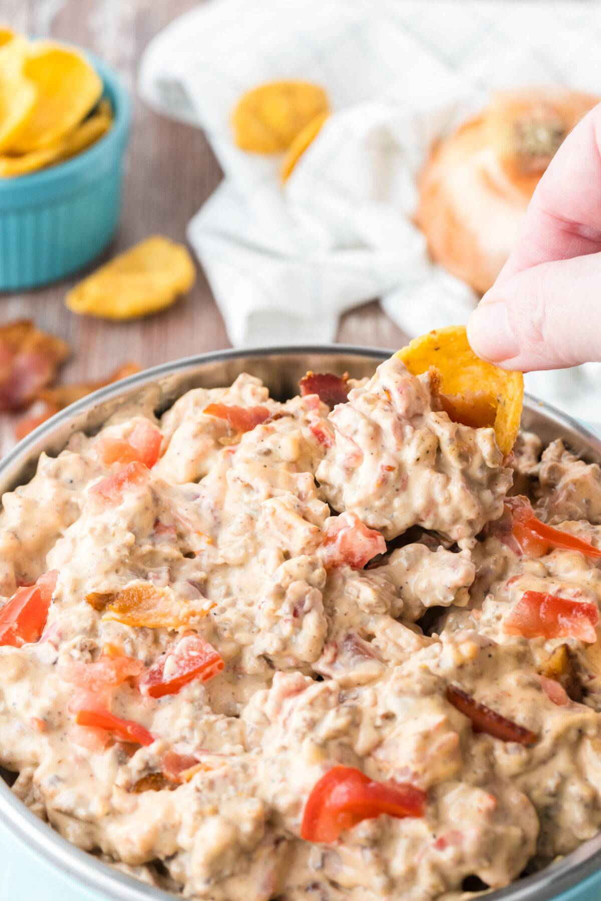 bacon cheeseburger dip in a bowl with a chip scooping