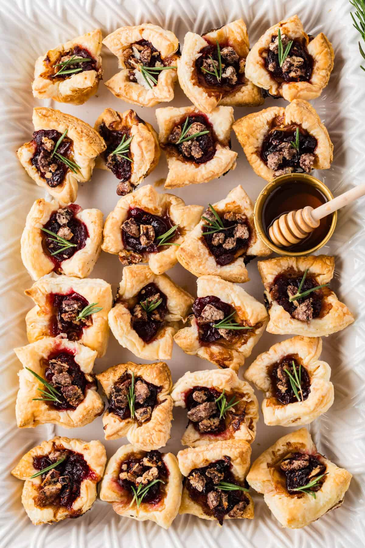 cranberry brie bites with springs of rosemary and honey drizzled over the top
