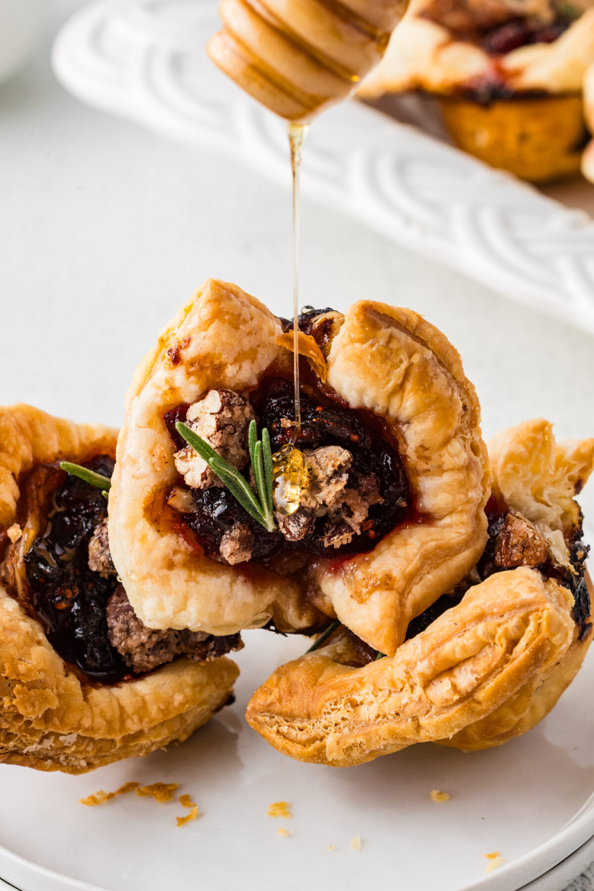 cranberry brie bites with springs of rosemary and honey drizzled over the top