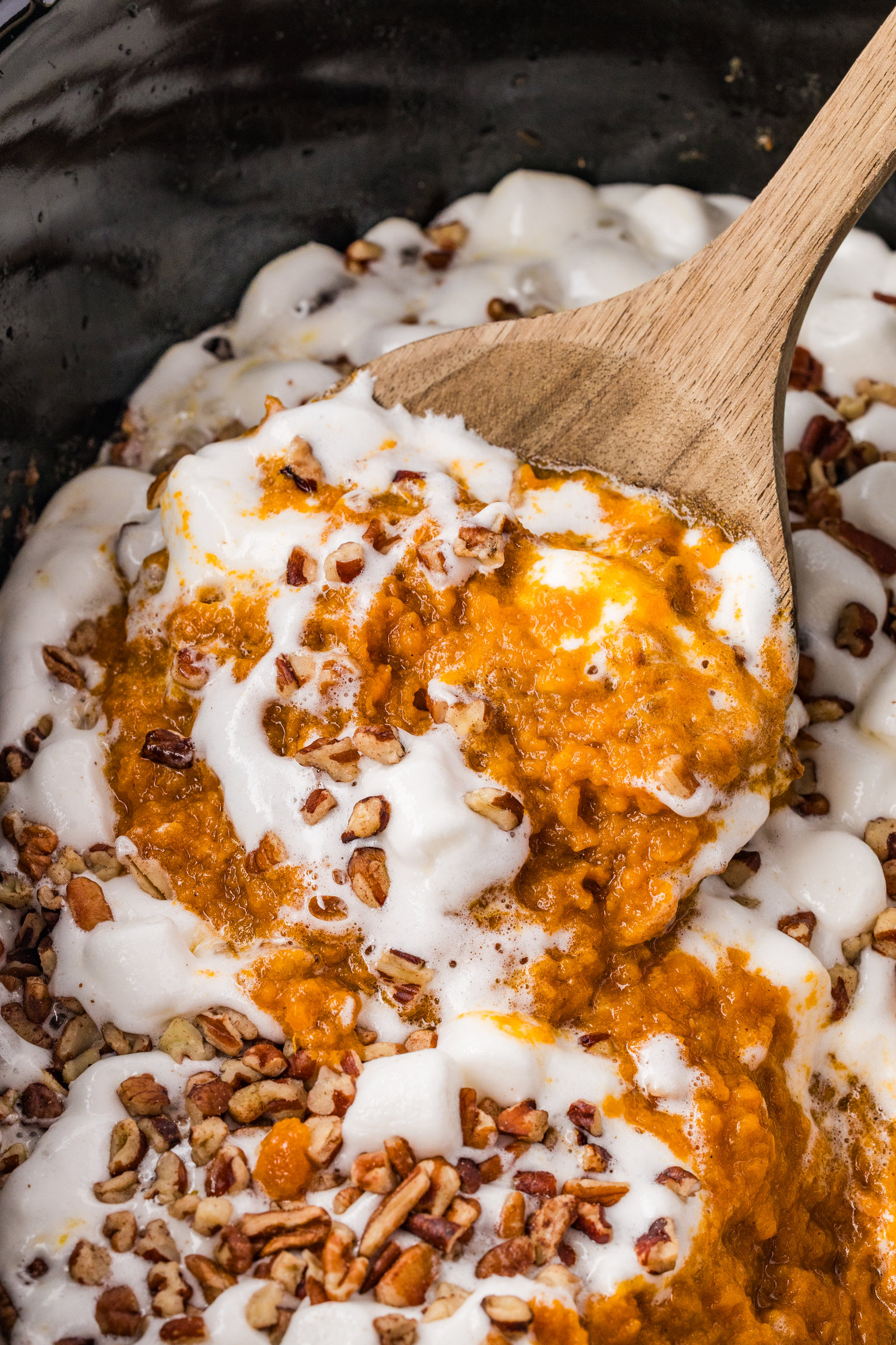 a wooden spoon full of crockpot sweet potato casserole