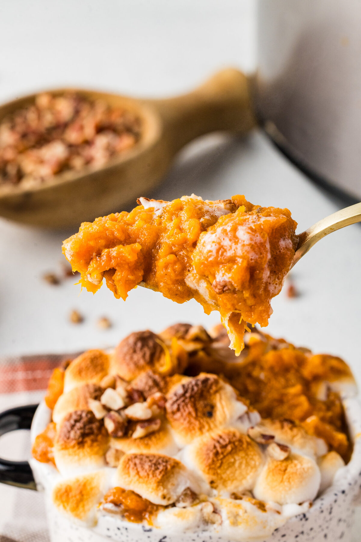 a bite of sweet potato casserole on a fork over a small ramekin