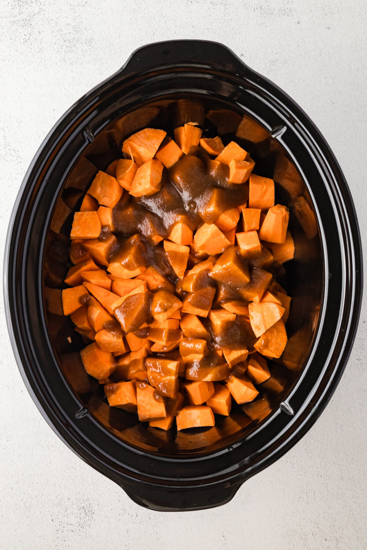 sugar butter mixture poured over sweet potatoes in crockpot