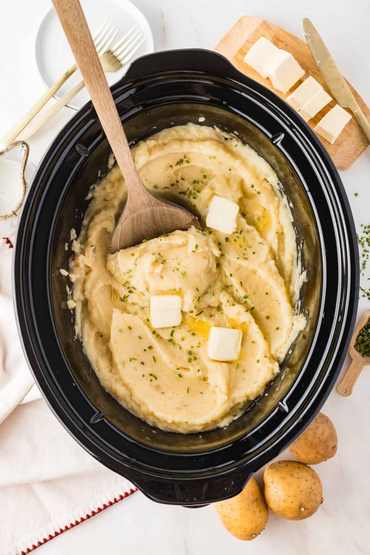 slow cooker mashed potatoes with a wooden spoon in the pot