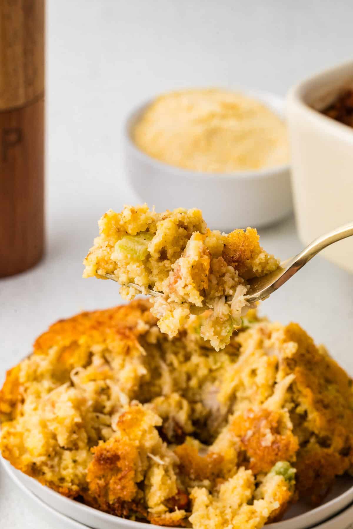 bite of cornbread dressing over a white plate of dressing
