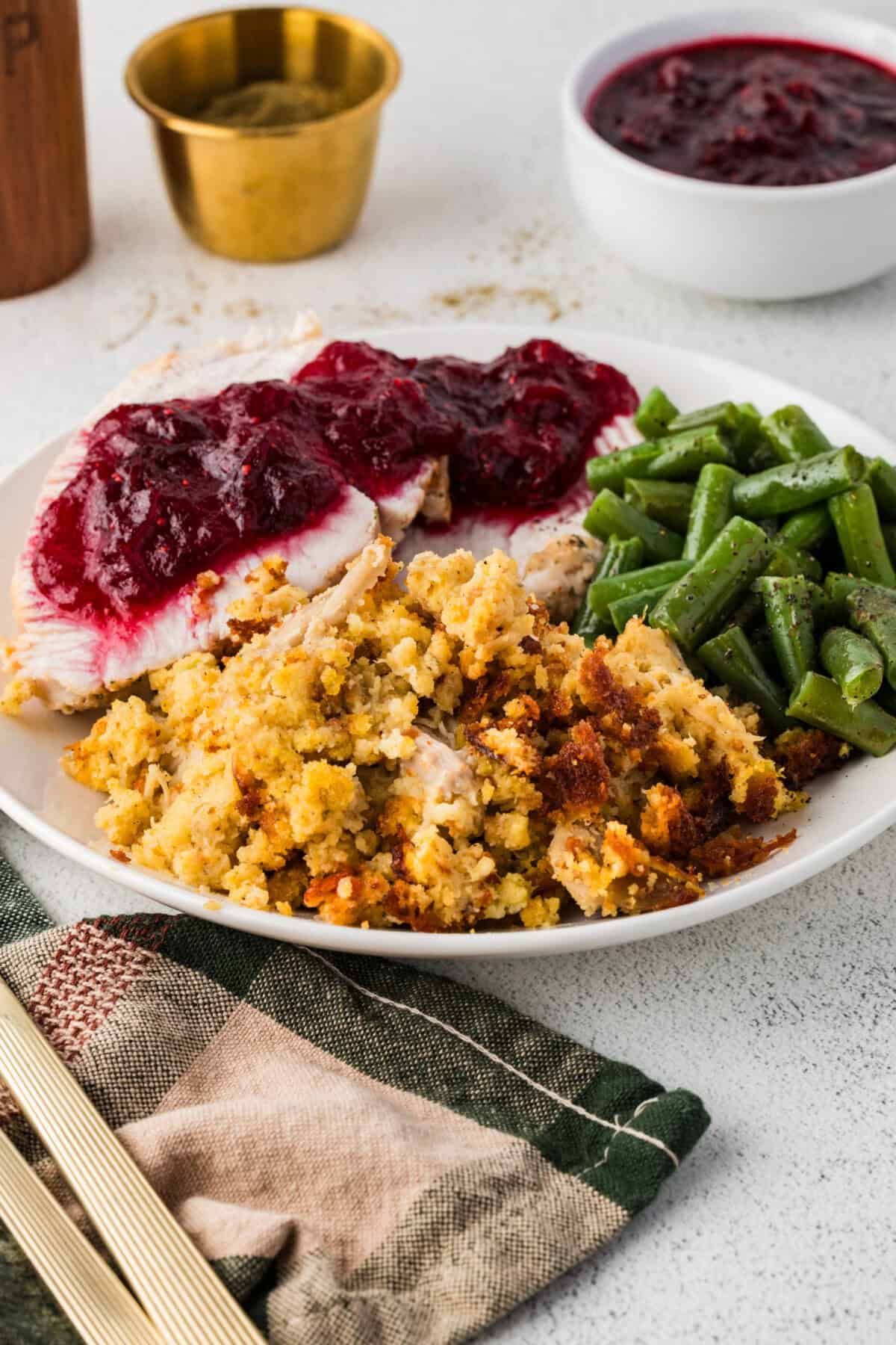 southern cornbread dressing on a plate with turkey, cranberry sauce and green beans