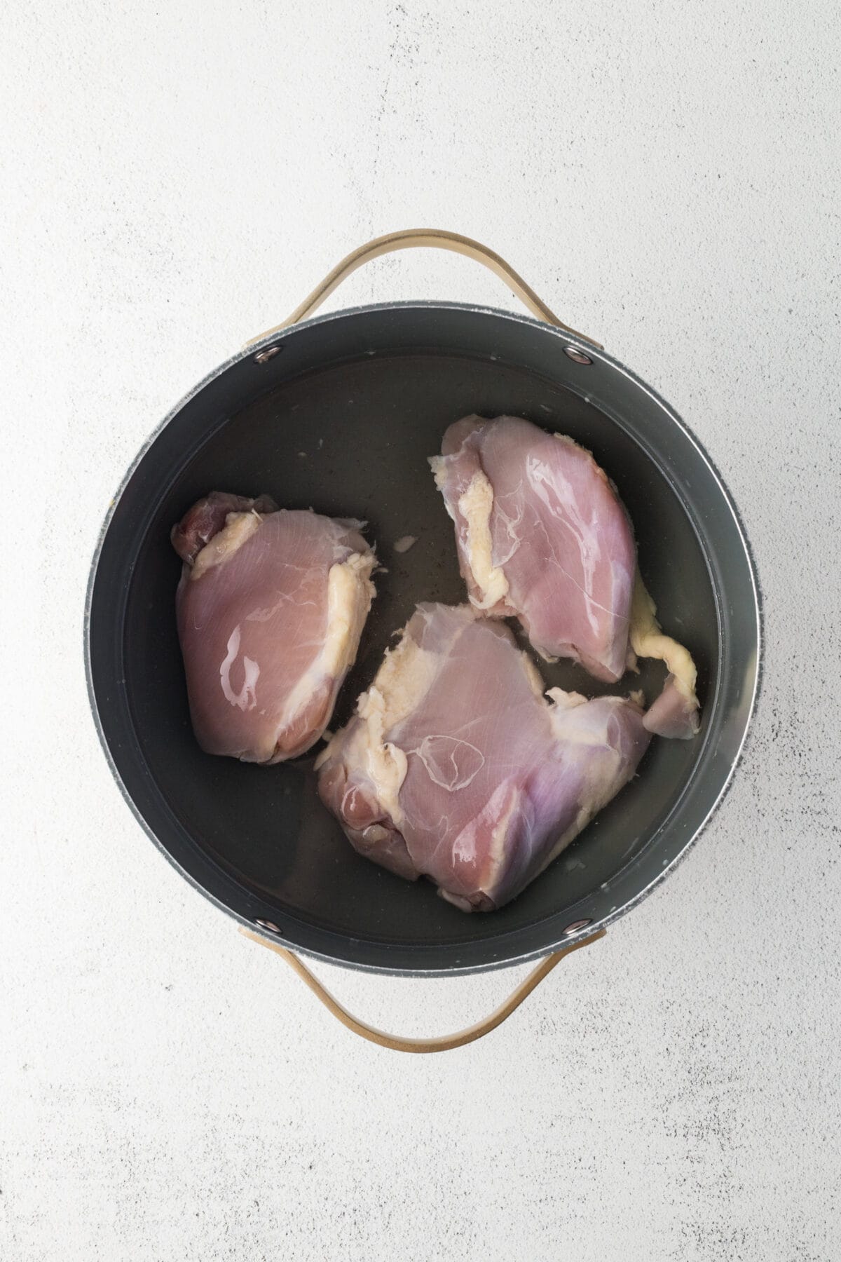 chicken thighs in water in a pot