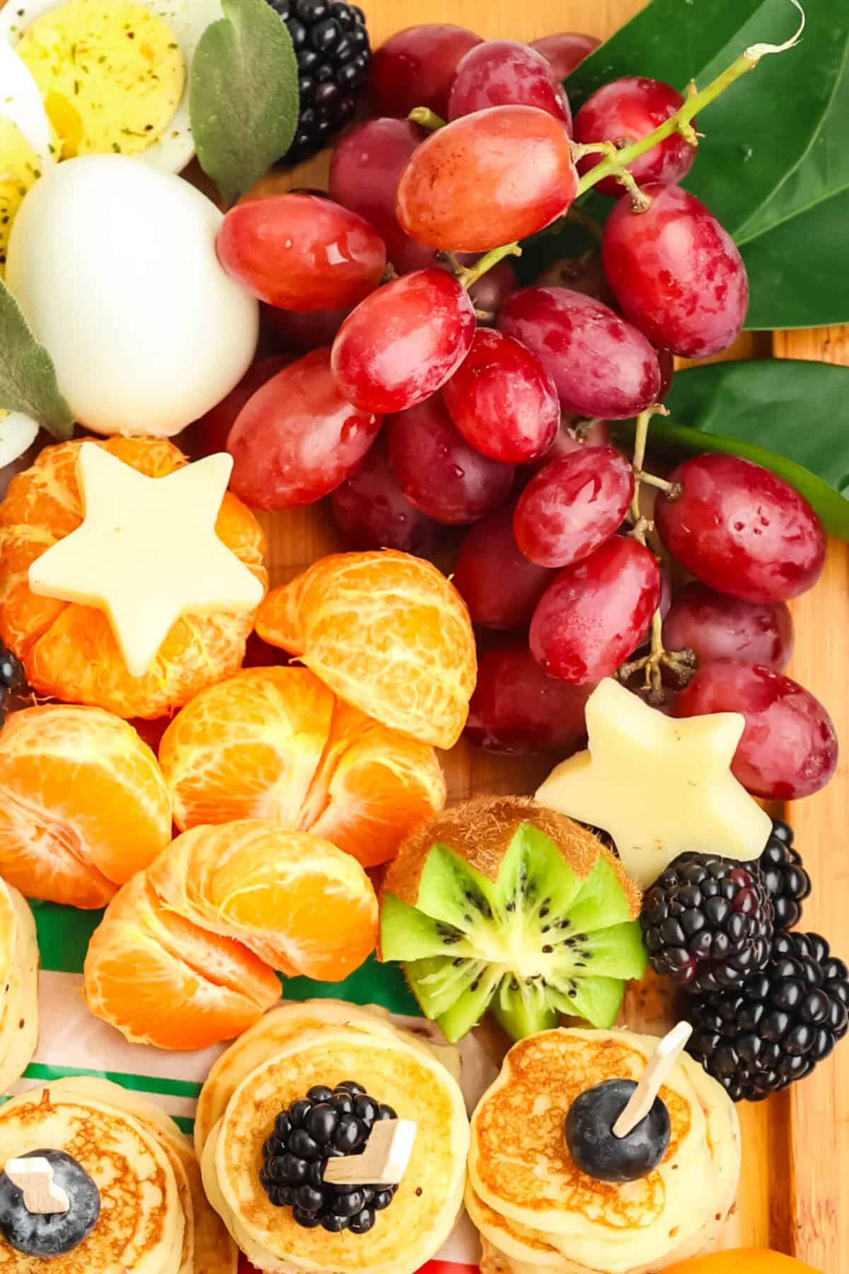 cuties and cheese stars and kiwi and grapes on a breakfast charcuterie board