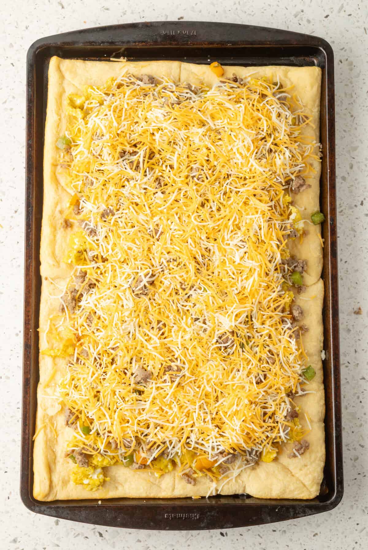 shredded cheese on top of the sausage and veggies