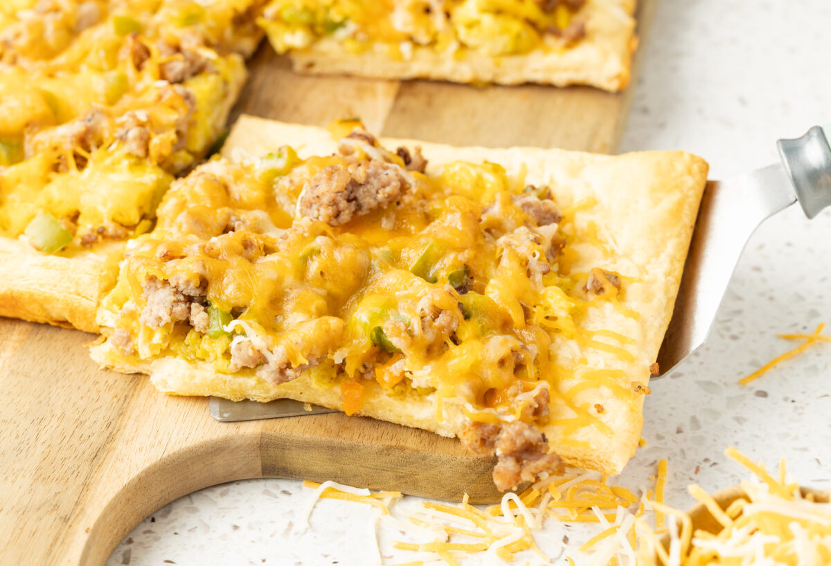 slice of breakfast pizza on a cutting board