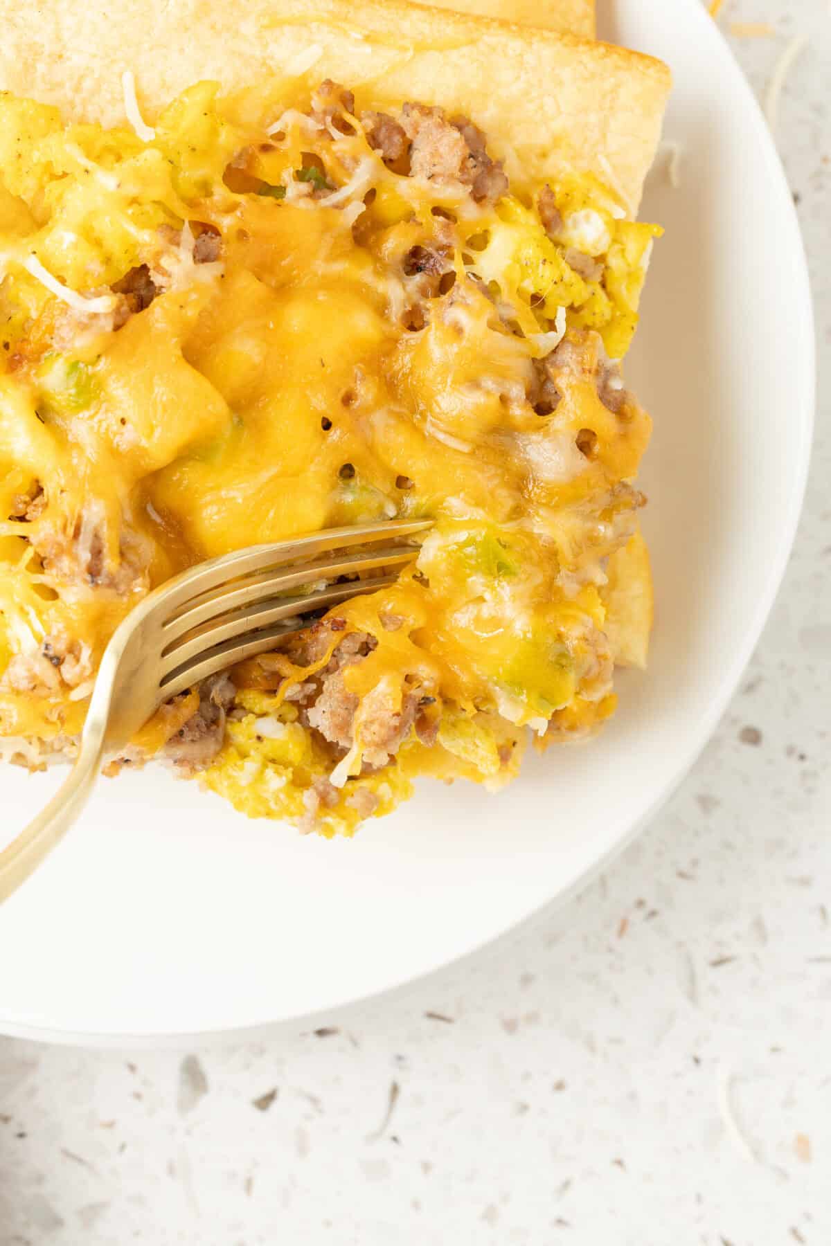 a fork cutting a bite out of breakfast pizza